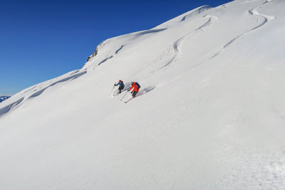 people carrying snowboards under a sunny sky