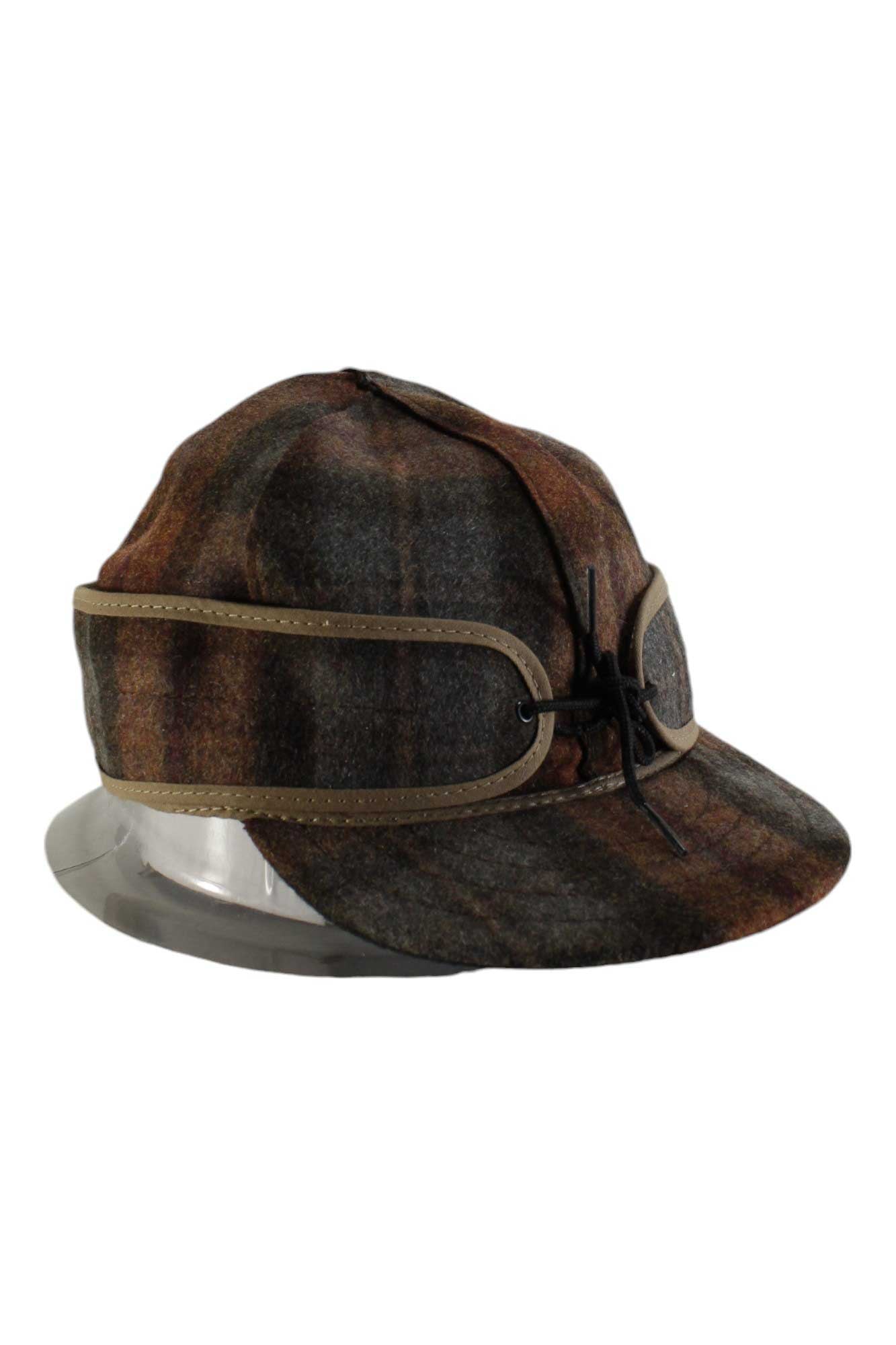 The Stormy Kromer Original Cap is a wool hat in brown, olive, and gray with a rounded crown, short brim, and leather bow strap across the front—an outdoor classic.