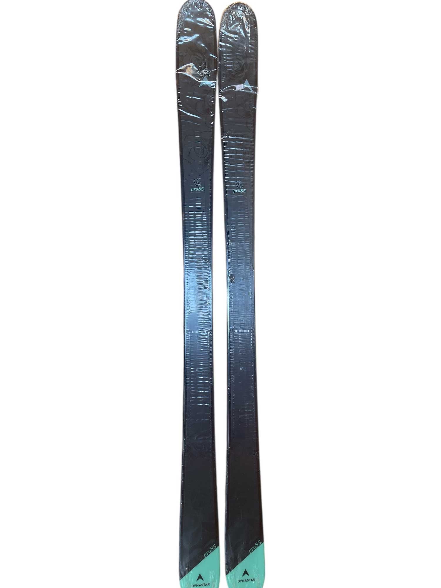 A pair of Dynastar Women's E-Pro 85 Freeride Skis in black and turquoise stand upright on a white background. They feature rounded tips and subtly textured bases.