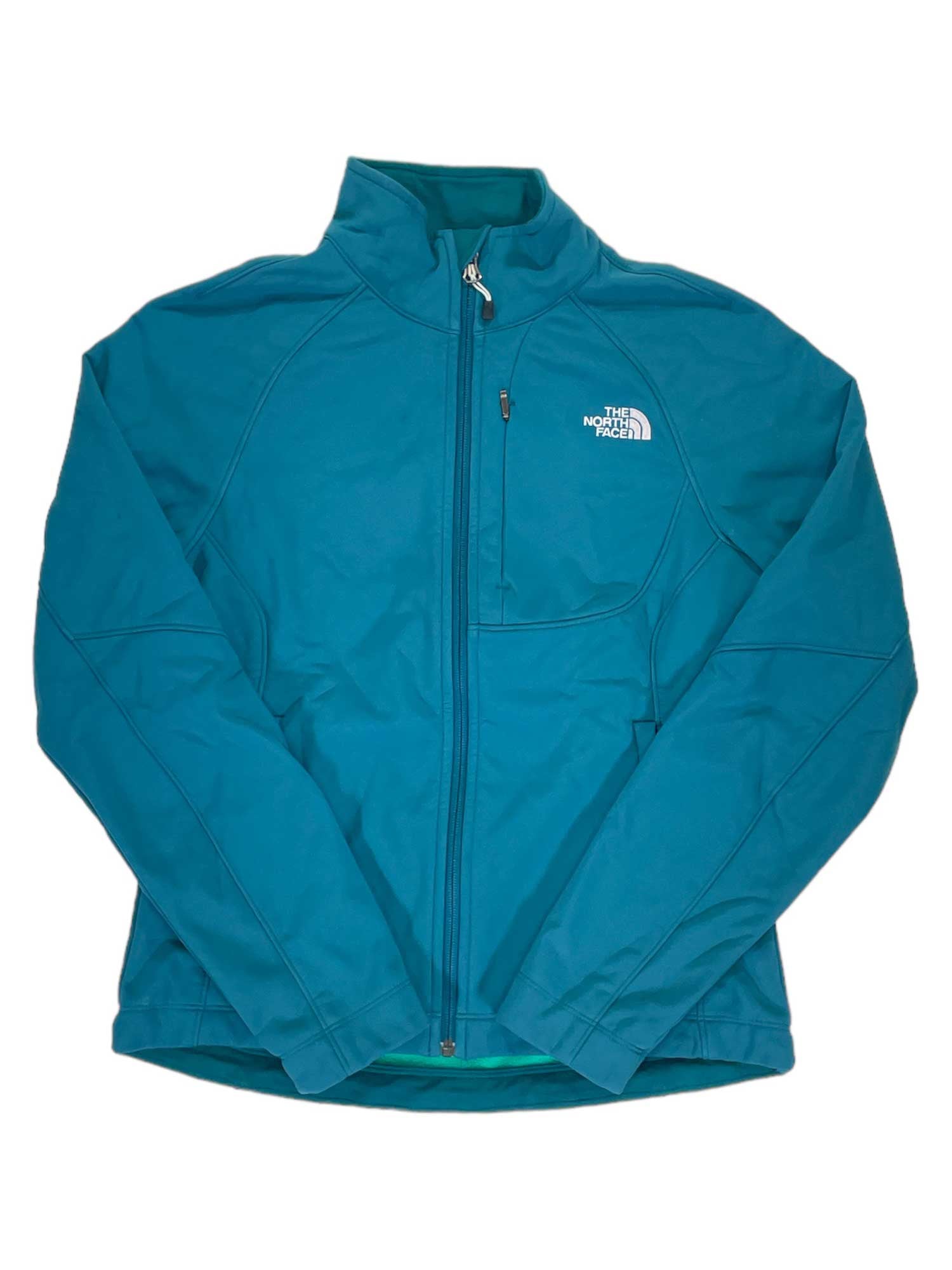 A teal Women's Apex Bionic Soft-Shell Jacket by The North Face, featuring a front zipper, high collar, zippered chest pocket, and white logo on the left chest, is laid flat on a white background.