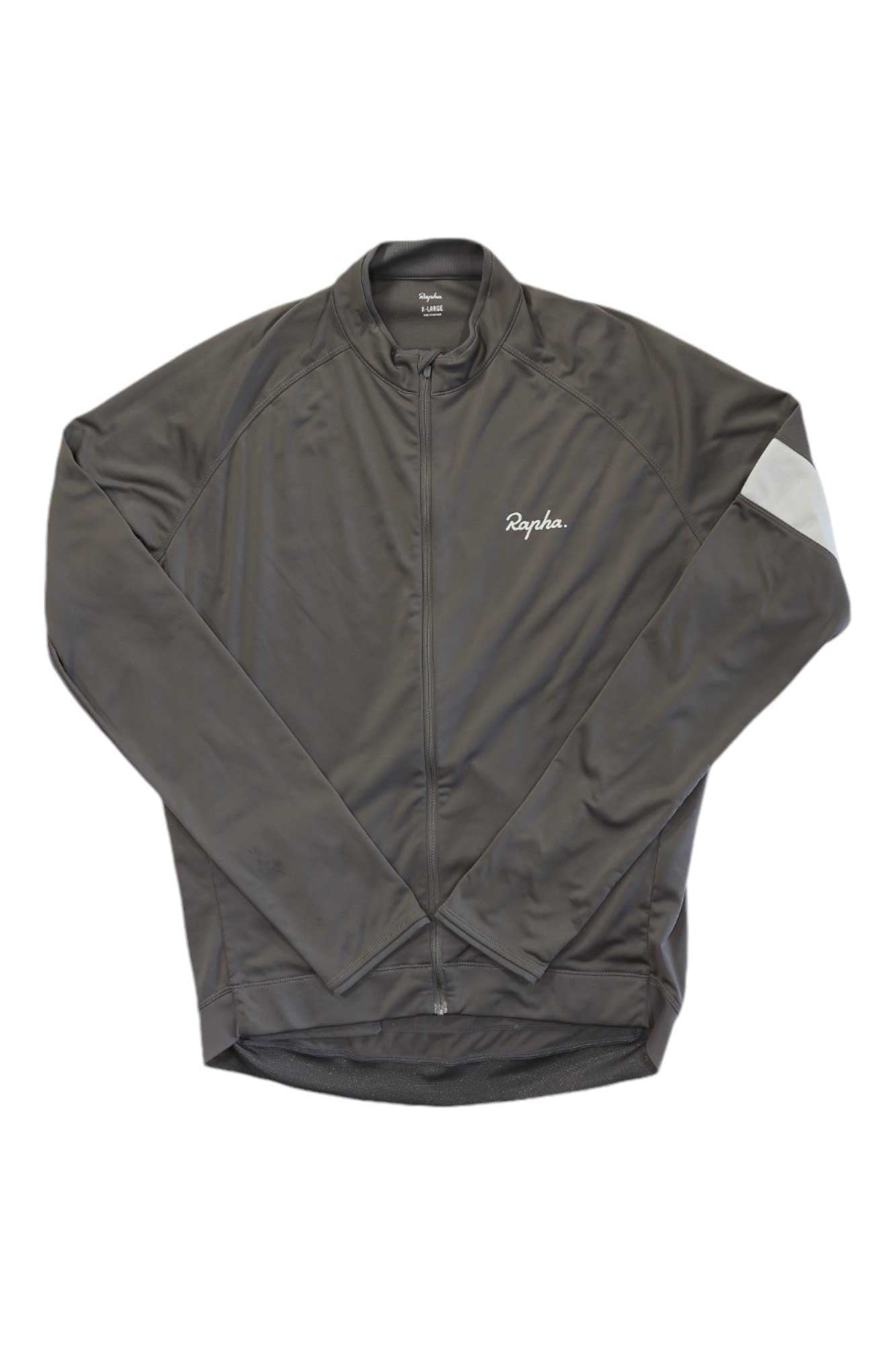 A Rapha Mens Core Long Sleeve Jersey in dark gray, with moisture-wicking fabric, full front zipper, small white chest logo, and light gray diagonal stripe on the left arm, is laid flat on a white background.