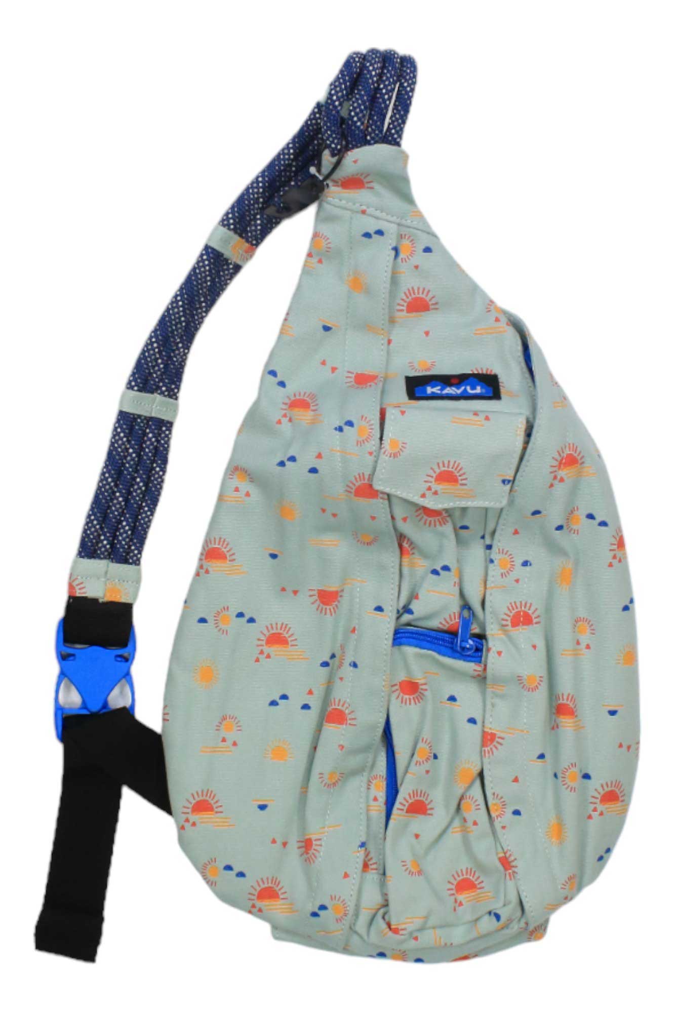 A light green KAVU Womens Rope Bag featuring a blue adjustable rope shoulder strap, blue buckle, red suns and orange clouds pattern, front zipper pocket, and a small black patch with the KAVU logo.