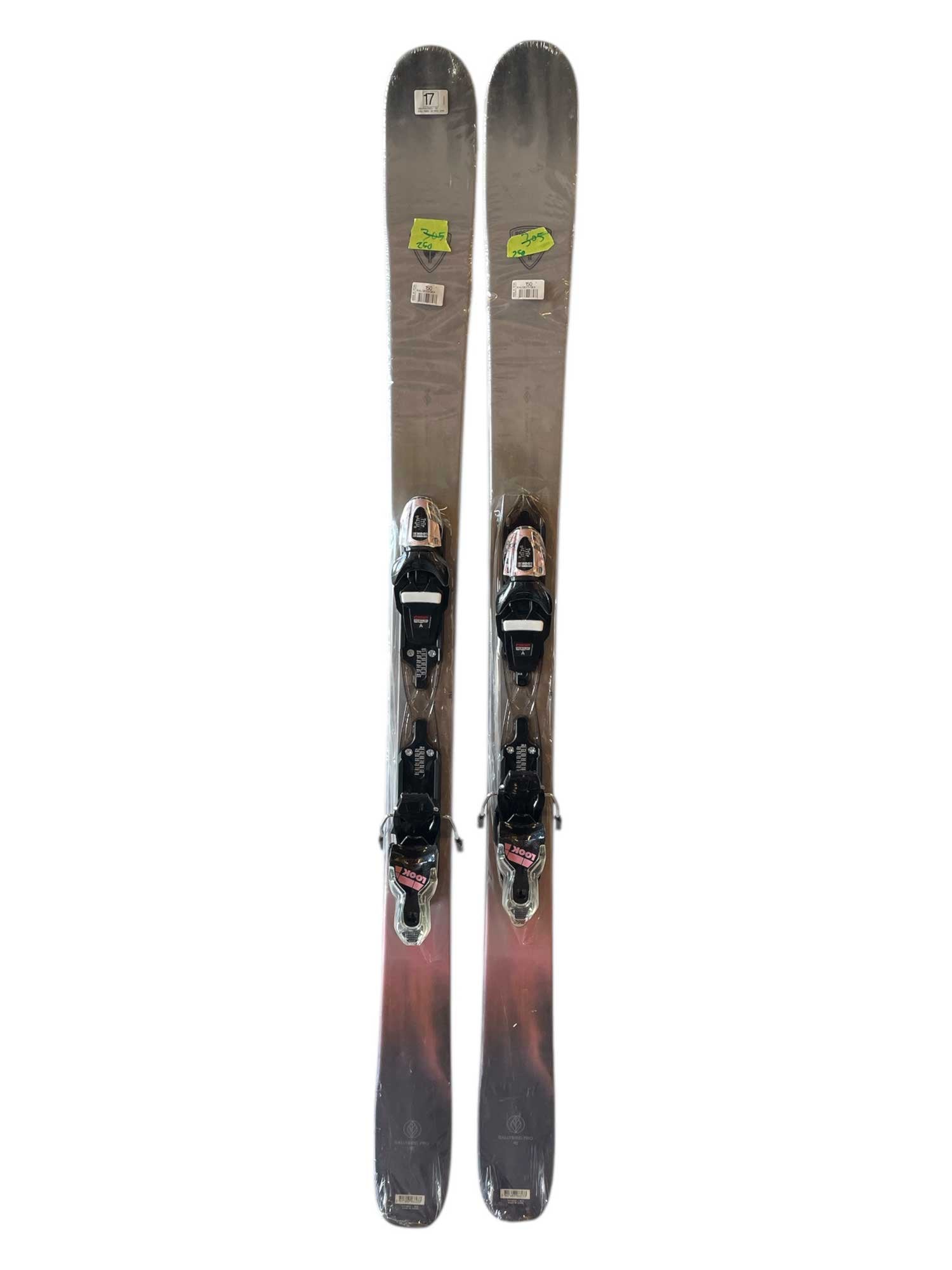 A pair of Rossignol Women's Rallybird 90 W Skis with Xpress 10 GripWalk Bindings '24, shown from above in gray and black with price stickers near the rounded, upturned tips designed for all-mountain performance.
