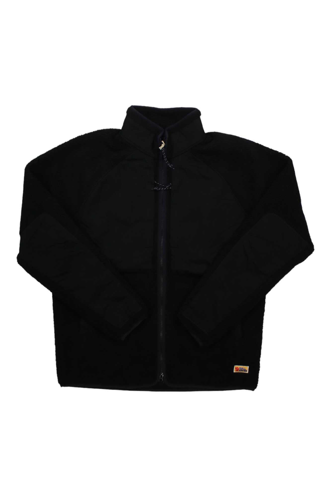 The Fjallraven Mens Vardag Pile Jacket, shown laid flat on a white background, is a black zip-up fleece made from recycled polyester with long sleeves, a high collar, and a small rectangular tag near the hem.