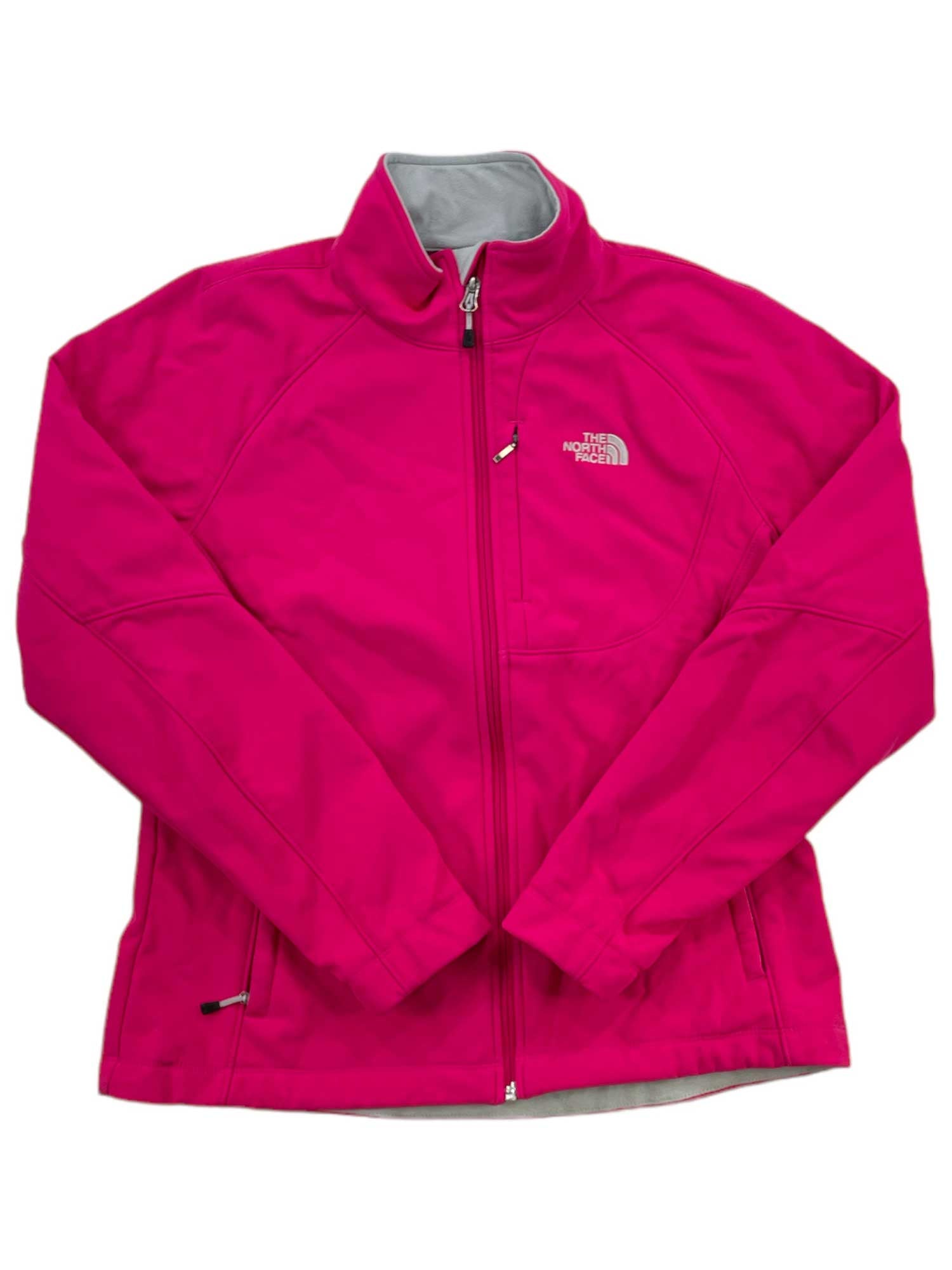 A bright pink Women's Apex Bionic Soft-Shell Jacket by The North Face, featuring a front zipper, high collar, and zippered side pockets. Displayed flat on a white background, this windproof jacket offers stylish protection from the elements.
