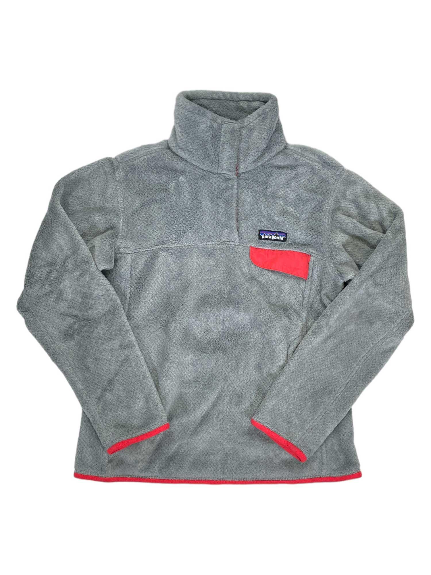 The Women's Re-Tool Snap-T Pullover is a gray fleece made from recycled polyester, featuring a high collar, long sleeves, red-trimmed chest pocket and cuffs, hem with red trim, and a small rectangular logo on the chest pocket.