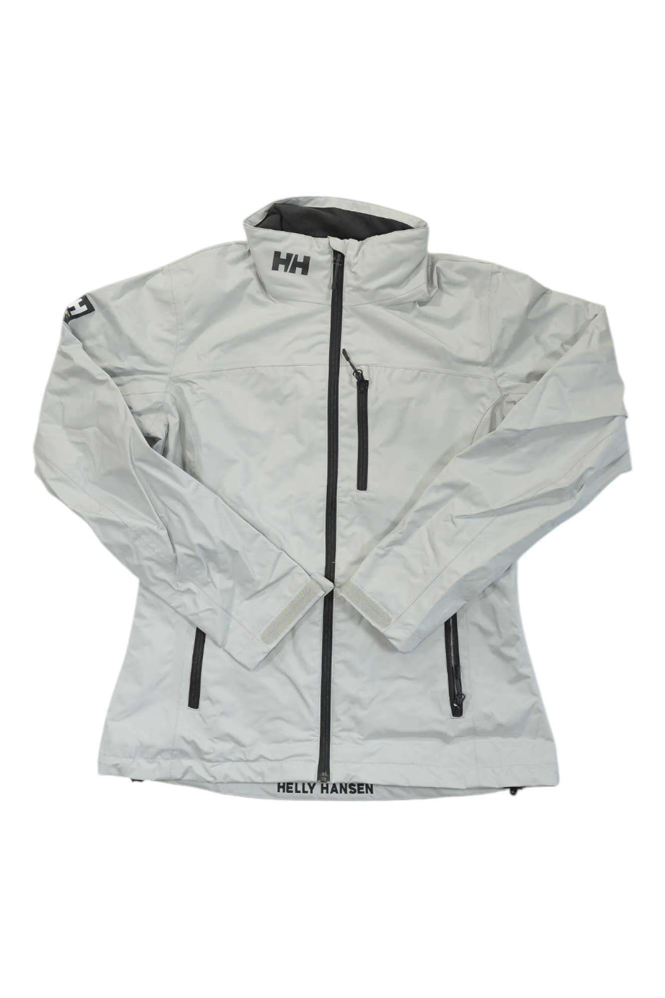 The Helly Hansen Womens Crew Jacket in light gray features a front zipper, chest and side zip pockets, and brand logos on the left chest and hem—a stylish yet functional choice for outdoor wear.