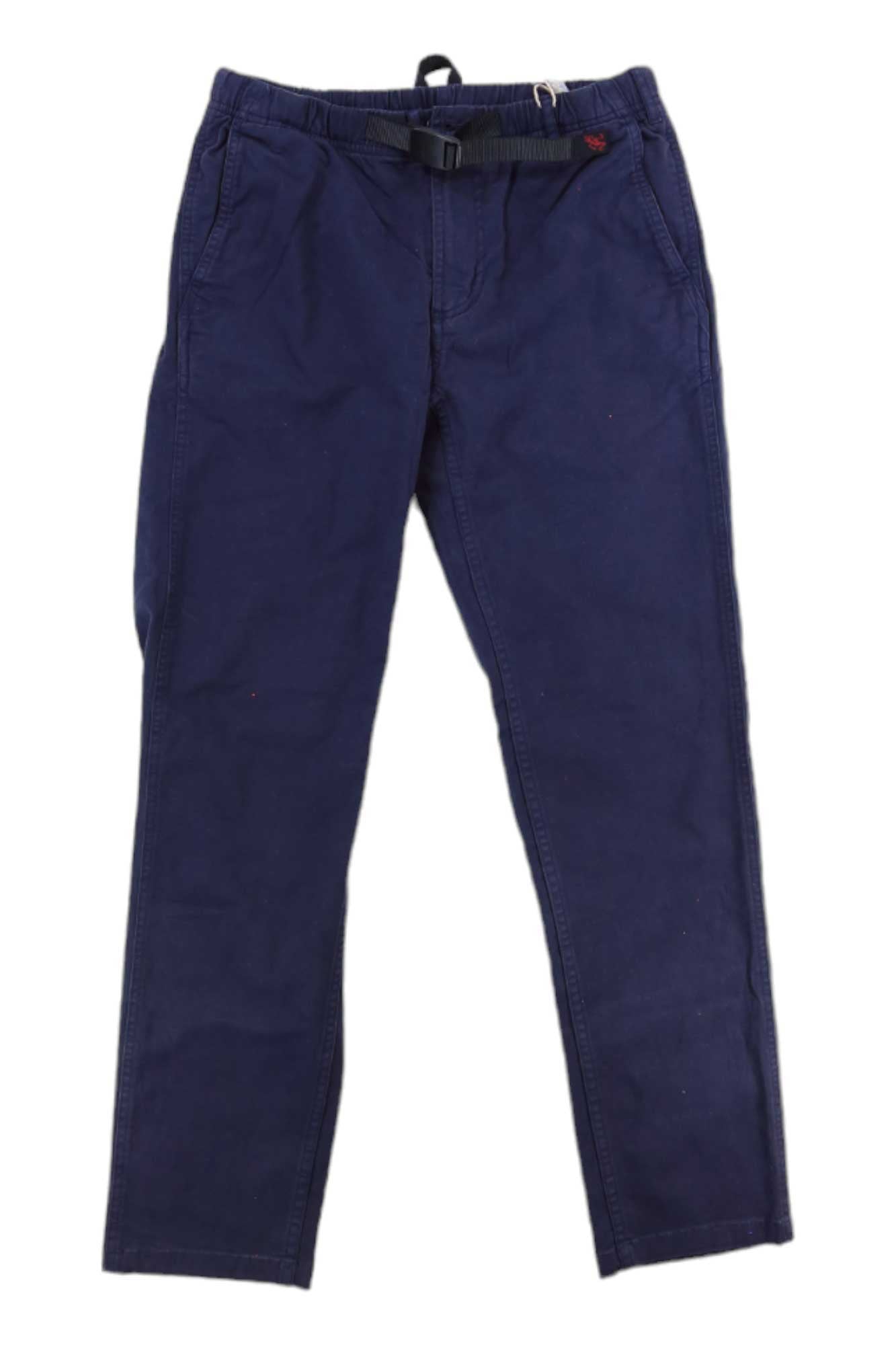 The Gramicci Womens Tapered Pant in dark blue cotton stretch twill features side pockets and a black belt, shown laid flat on a white background.