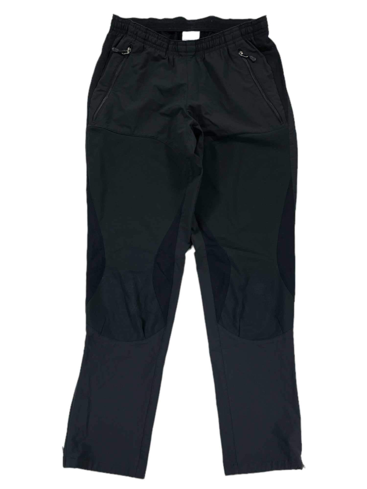 Women's Integral Pants in black, featuring windproof fabric, zippered front pockets, reinforced knees, and an elastic waistband. The Nordic ski pants are displayed flat on a white background.