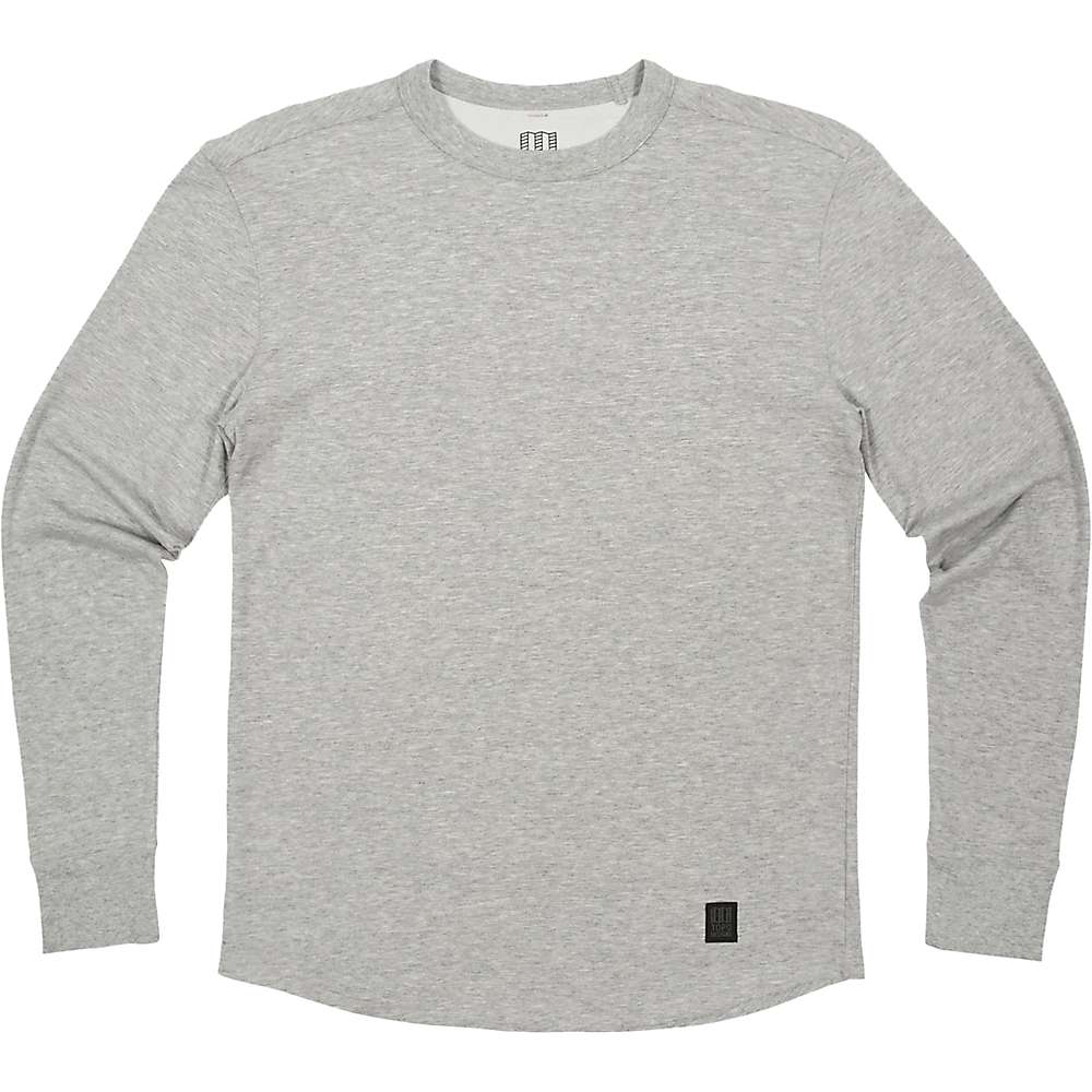 A Topo Designs Men's Long Sleeve Tech Tee in Gray Heather is laid flat on a white background. The quick-drying crewneck shirt has a small black rectangular patch near the bottom hem on one side.