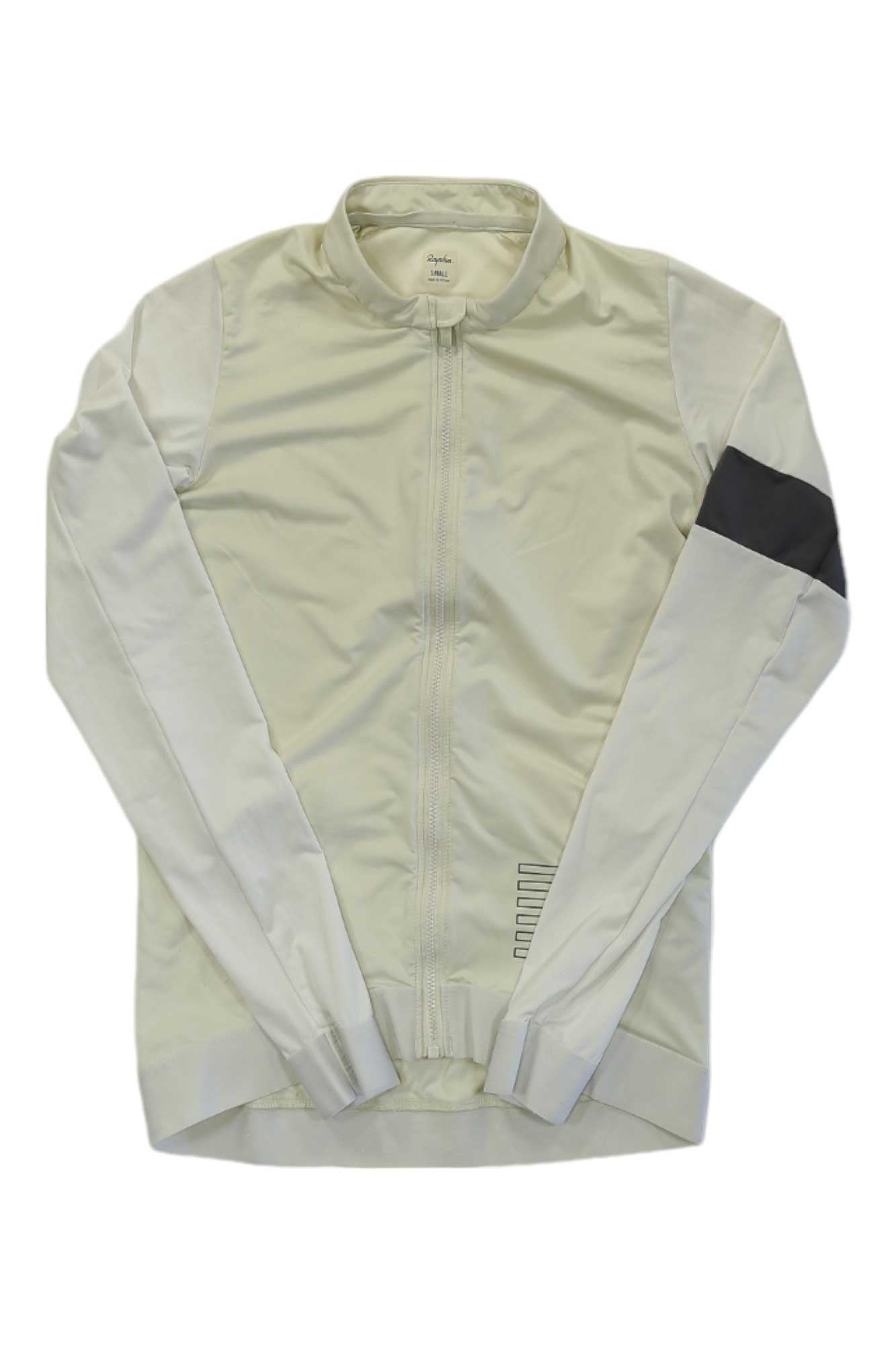The Rapha Mens Pro Team Long Sleeve Training Jersey is a light beige zip-up cycling jacket with a collar, long sleeves, and a dark grey band on the upper left arm, displayed flat on a white background.