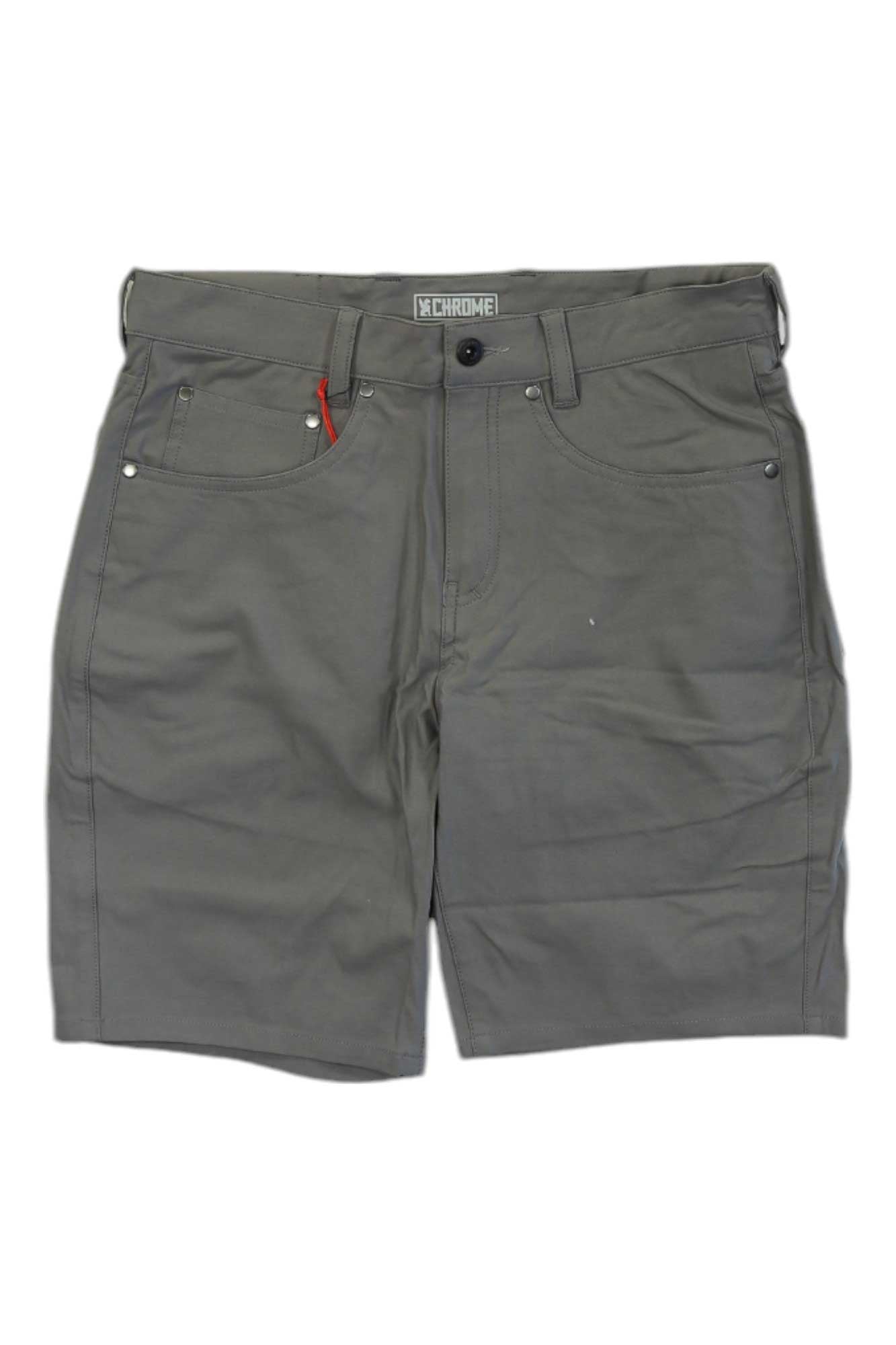 The Chrome Industries Mens Madrona Short is a gray casual short for men featuring a button and zipper closure, belt loops, front and back pockets, a small red tag by the right front pocket, and quick-dry fabric for all-day comfort.