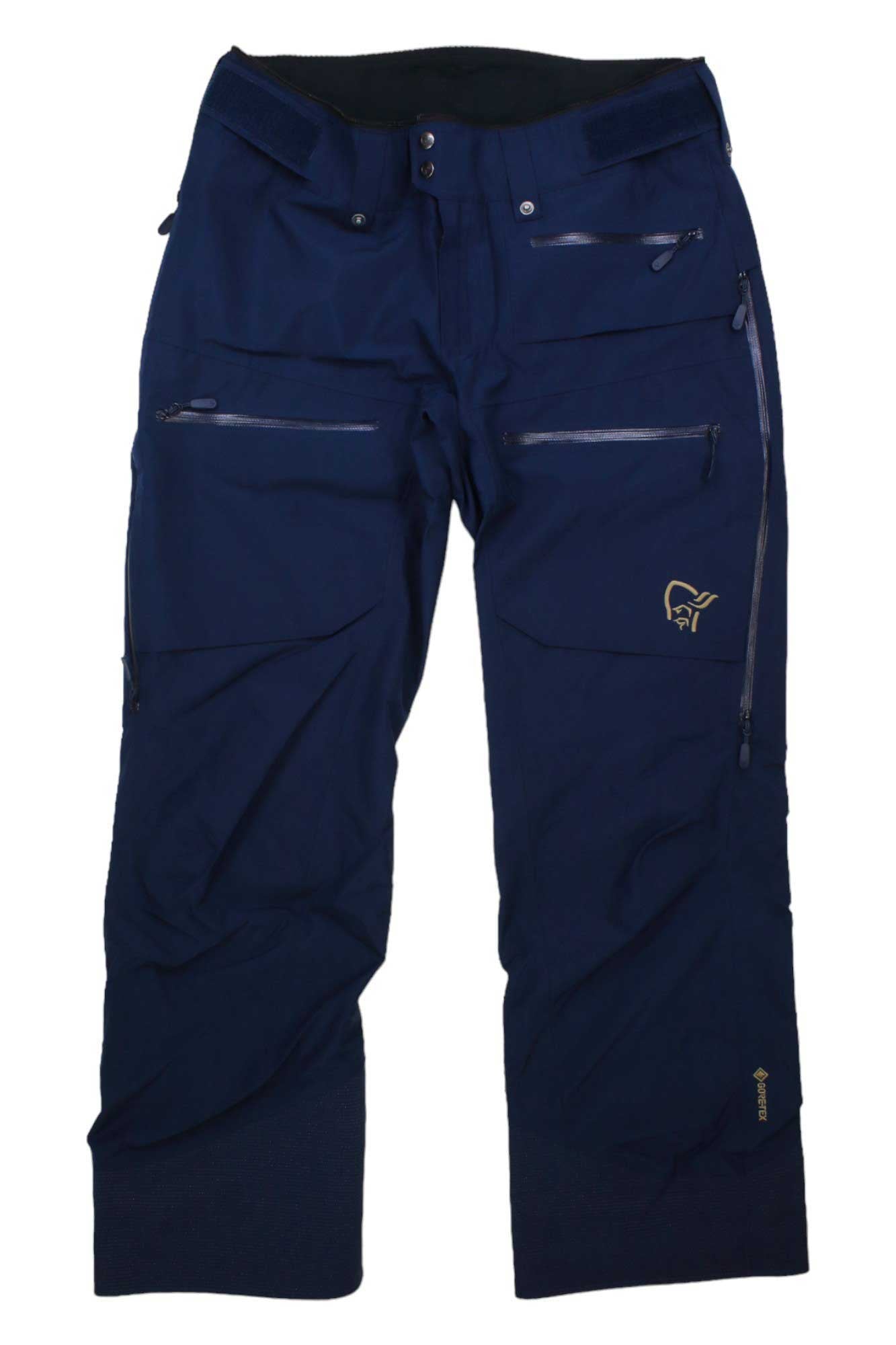The Norrona Womens Lofoten GORE-TEX Insulated Snow Pants are navy blue and feature waterproof fabric, multiple zippered pockets, reinforced knees, and a small embroidered logo on the upper right thigh.