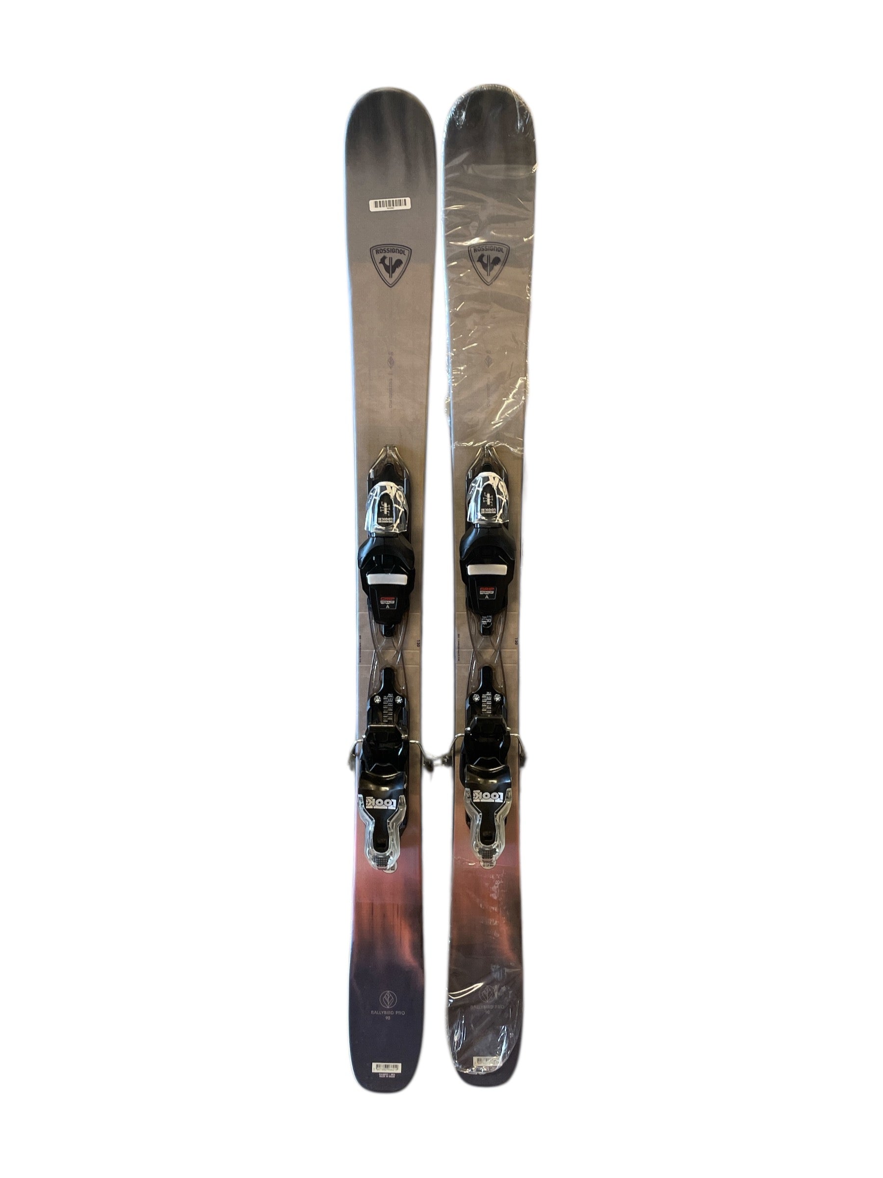 A pair of gray Rossignol Rallybird Pro 90 Ski + Xpress 7 Bindings, side by side on a white background. These pre-mounted skis have a subtle gradient design with brand logos near the tips and include black bindings.
