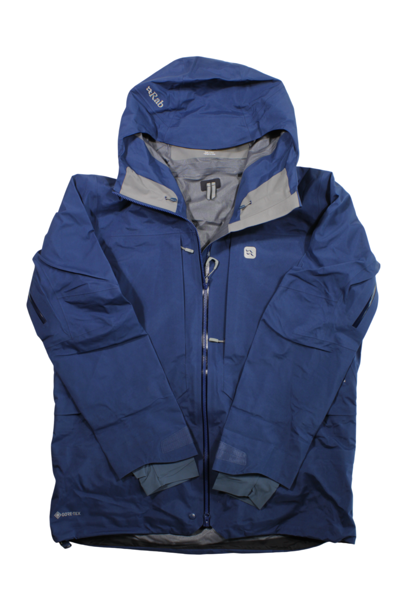 The Rab Mens Khroma Converge Jacket is a blue waterproof shell with a hood, front zipper, multiple pockets, and gray lining. Laid flat, it displays logos and GORE-TEX branding on the sleeve and chest.