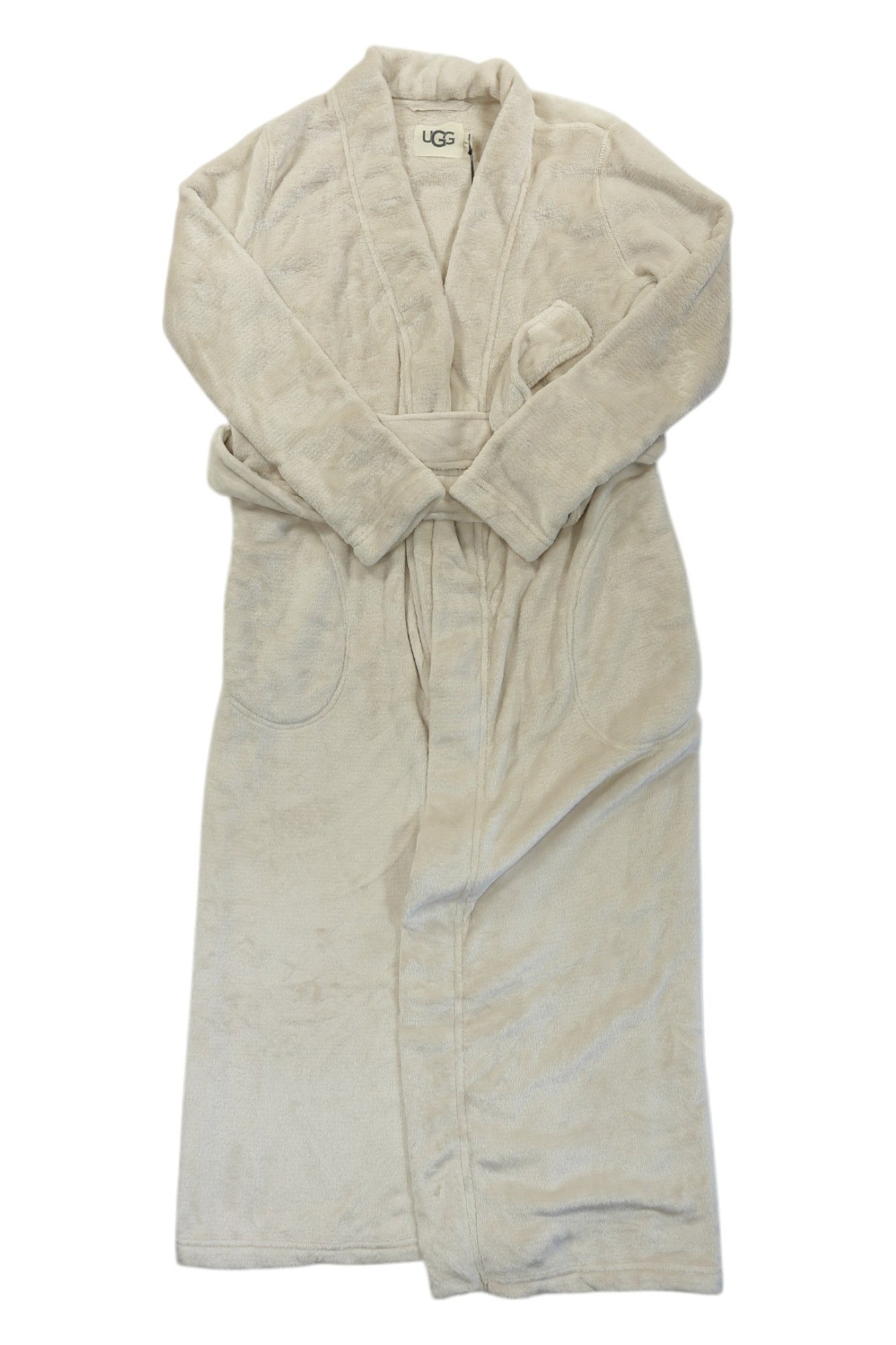The Ugg Womens Marlow Robe is a long, light beige robe with a shawl collar, two front pockets, and a matching belt. It’s made from premium fabric and shown flat on a white background with the UGG label visible at the neckline.