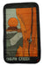 The Lacaida Rope Tarp features a stylized blanket design of a climber ascending an orange rock with the rope tarp below and the sun setting behind mesas. "INDIAN CREEK" is written at the bottom.