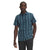 A man stands against a white background wearing The North Face Men's Hammetts II SS Shirt in blue and black plaid, paired with dark pants, with one hand in his pocket.
