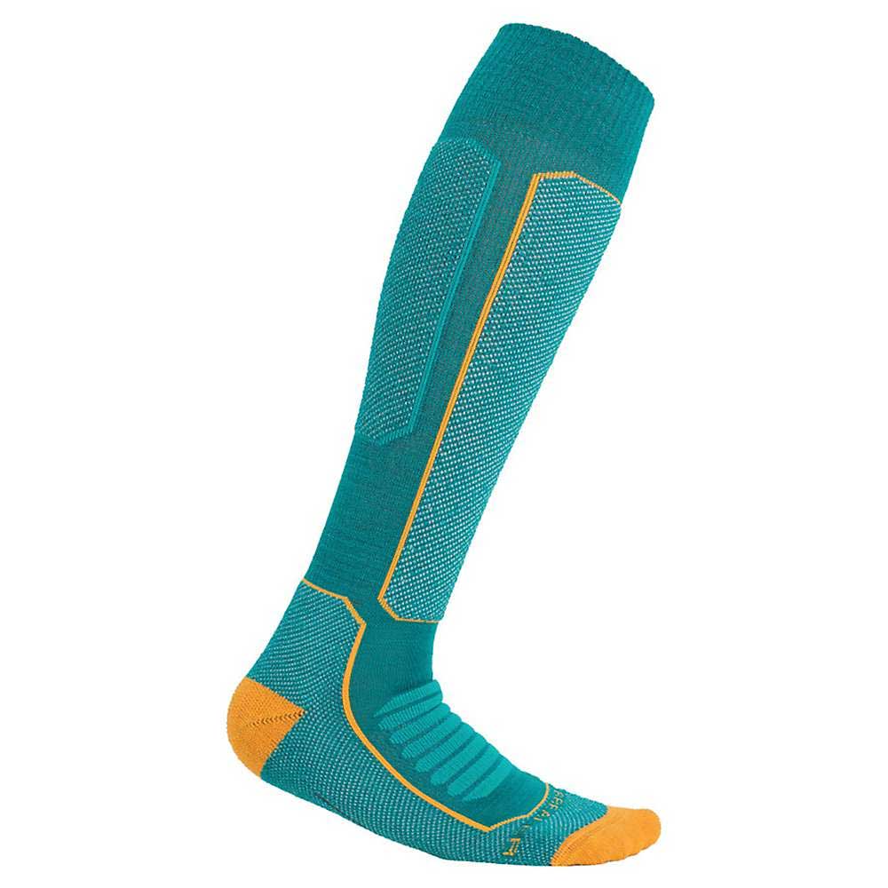 The Icebreaker Womens Ski+ Medium Over The Calf Sock is a single teal ski sock for women, featuring yellow accents on the toe, heel, and seams, with ribbed and padded sections for extra comfort and support.