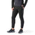 A person stands with hands in pockets, wearing Smartwool Men's Active Fleece Tech Pant in black, a black quilted jacket, and black and gray athletic shoes against a white background. Their head is not visible.