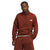 Wearing The North Face Mens Canyonlands 1/2 Zip Jacket in rust and matching fleece pants, a man stands against a plain white background, hands in pockets, looking at the camera.