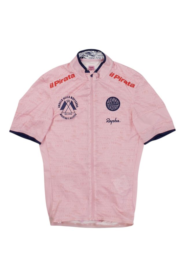 The Rapha Men’s Super Lightweight Jersey is a light pink, short-sleeve cycling jersey with a full front zipper, navy blue collar and sleeve trim, and chest logos including “il Pirata,” “Mamma Raduni,” and “Rapha.”.