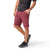 A man wears a black tie-dye tee, Smartwool Men's 10 Inch maroon shorts, and black trail sneakers, standing with one hand in his pocket against a white background.