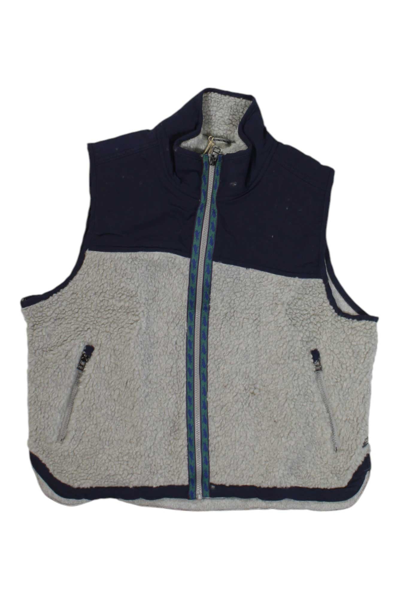 The Toad & Co Womens Sespe Sherpa Vest is a sleeveless fleece with a high collar, navy and light gray color block design, two zippered side pockets, and a patterned front zipper—ideal for outdoor layering.