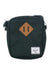 The Herschel Supply Company Heritage Crossbody Bag is small, rectangular, and dark green, made from EcoSystem recycled fabric with a brown leather diamond patch and a white Herschel label on the front.