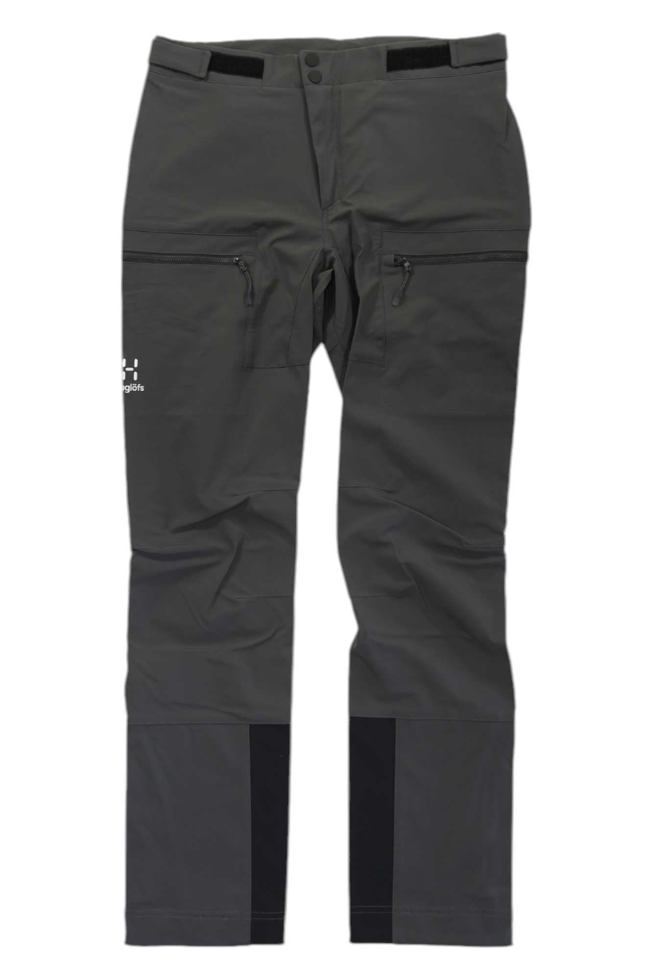 The Haglofs Womens Roc Sight Softshell Pant features dark grey fabric, black reinforced lower leg patches, zippered thigh pockets, and a small Haglöfs logo—perfect for hiking or climbing. Pants shown laid flat on a white background.