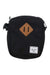 The Herschel Supply Company Heritage Crossbody Bag is a black, unisex bag with a tan diamond logo and white brand tag, made from EcoSystem recycled fabric for eco-friendly style.