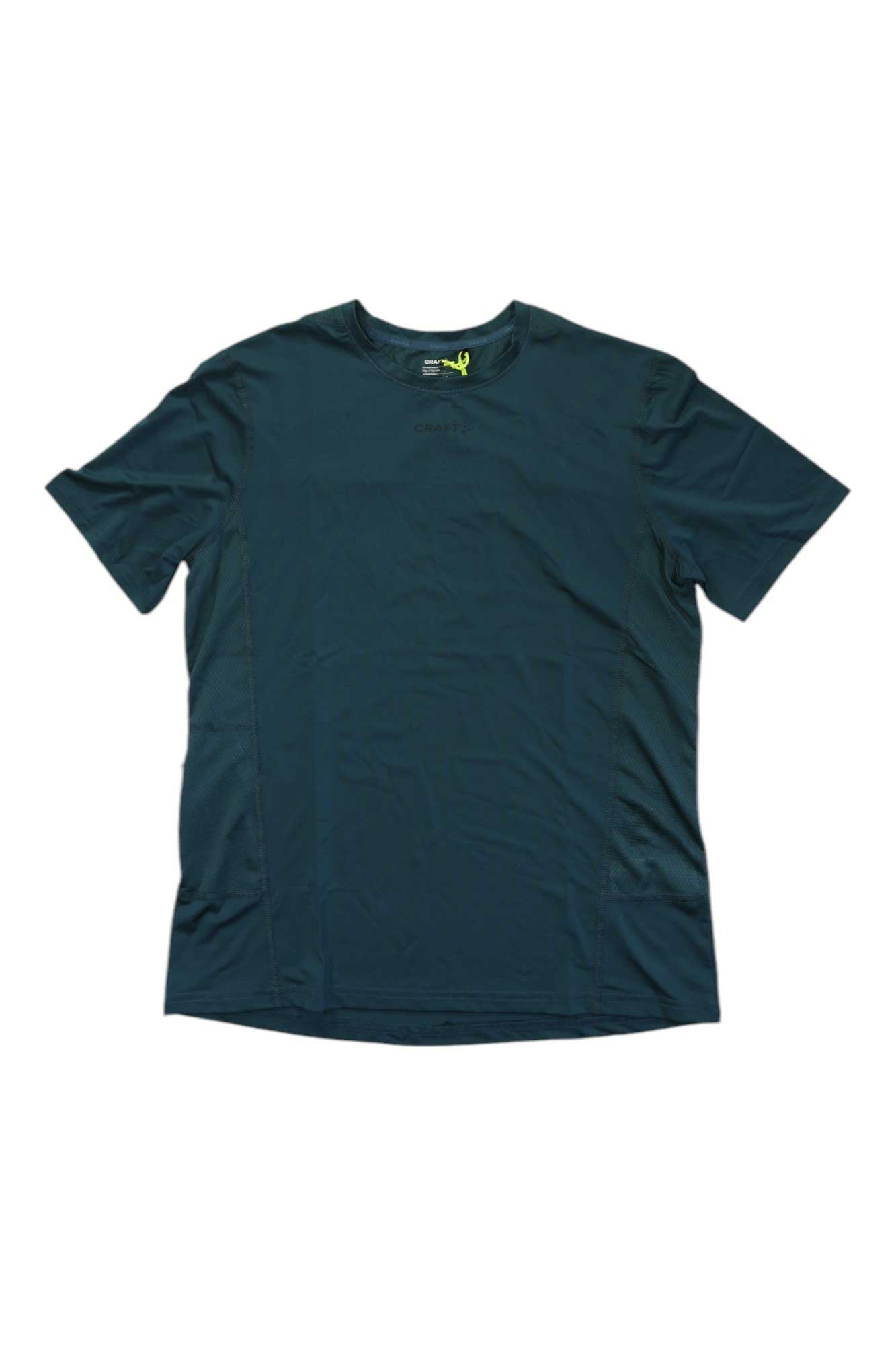 The Craft Sportswear Mens ADV Essence SS Tee is a dark green short-sleeve running shirt with a crew neck, laid flat on a white background. Made from soft recycled polyester, it offers moisture-wicking comfort and minimal visible detailing.