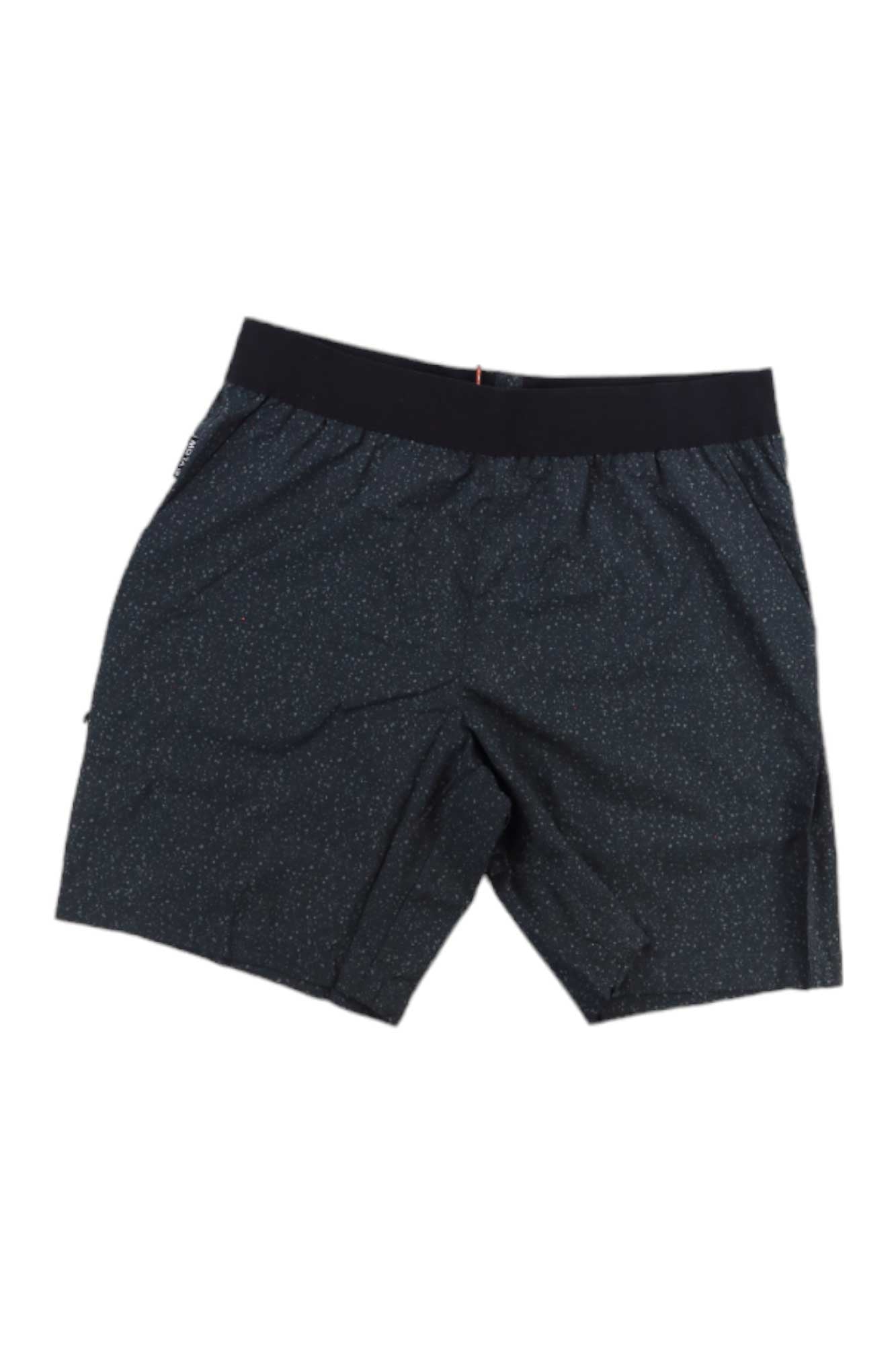 The Flylow Mens Safari 8.5 Inch Short features an elastic waistband and a subtle dotted pattern, ideal for mountain biking. These black athletic shorts provide sun protection and comfort, shown laid flat on a white background.