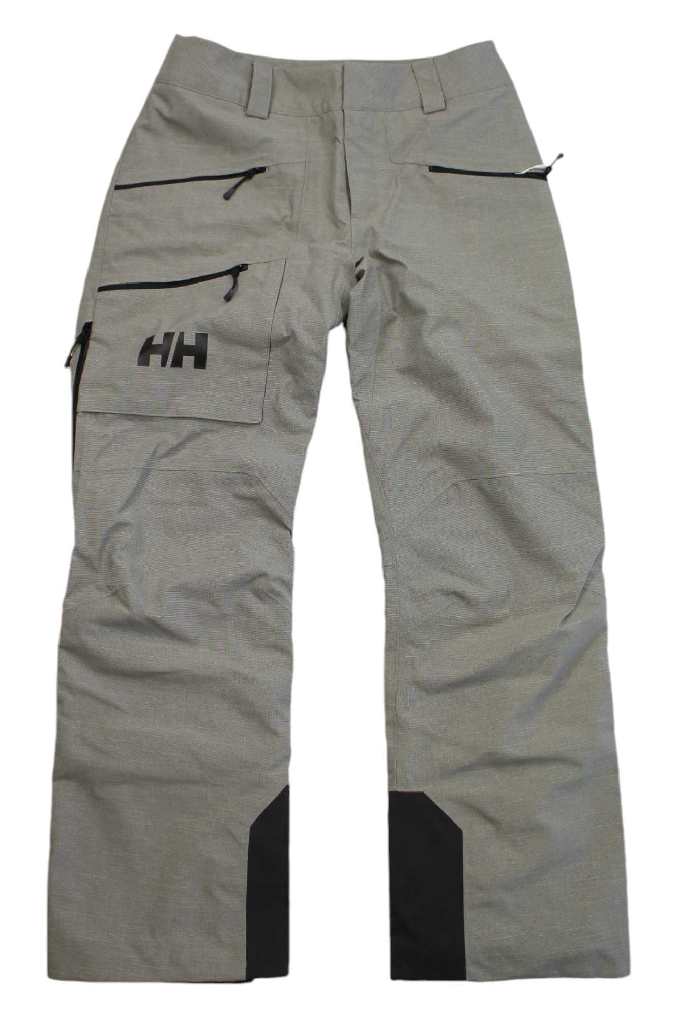 Light gray Helly Hansen Womens Powderqueen Pant, featuring multiple zippered pockets, black reinforced cuffs, and the HH logo on the left thigh pocket. Pants are displayed laid flat on a white background.