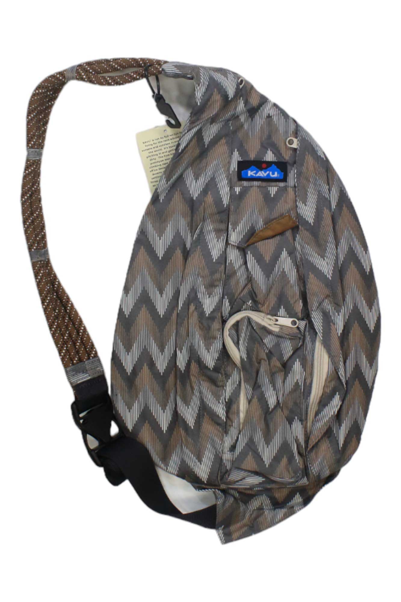 The KAVU Rope Sack, shown in brown and gray with a zigzag chevron pattern, features an adjustable rope strap and zippered pockets—ideal as a stylish travel sling pack on a white background.