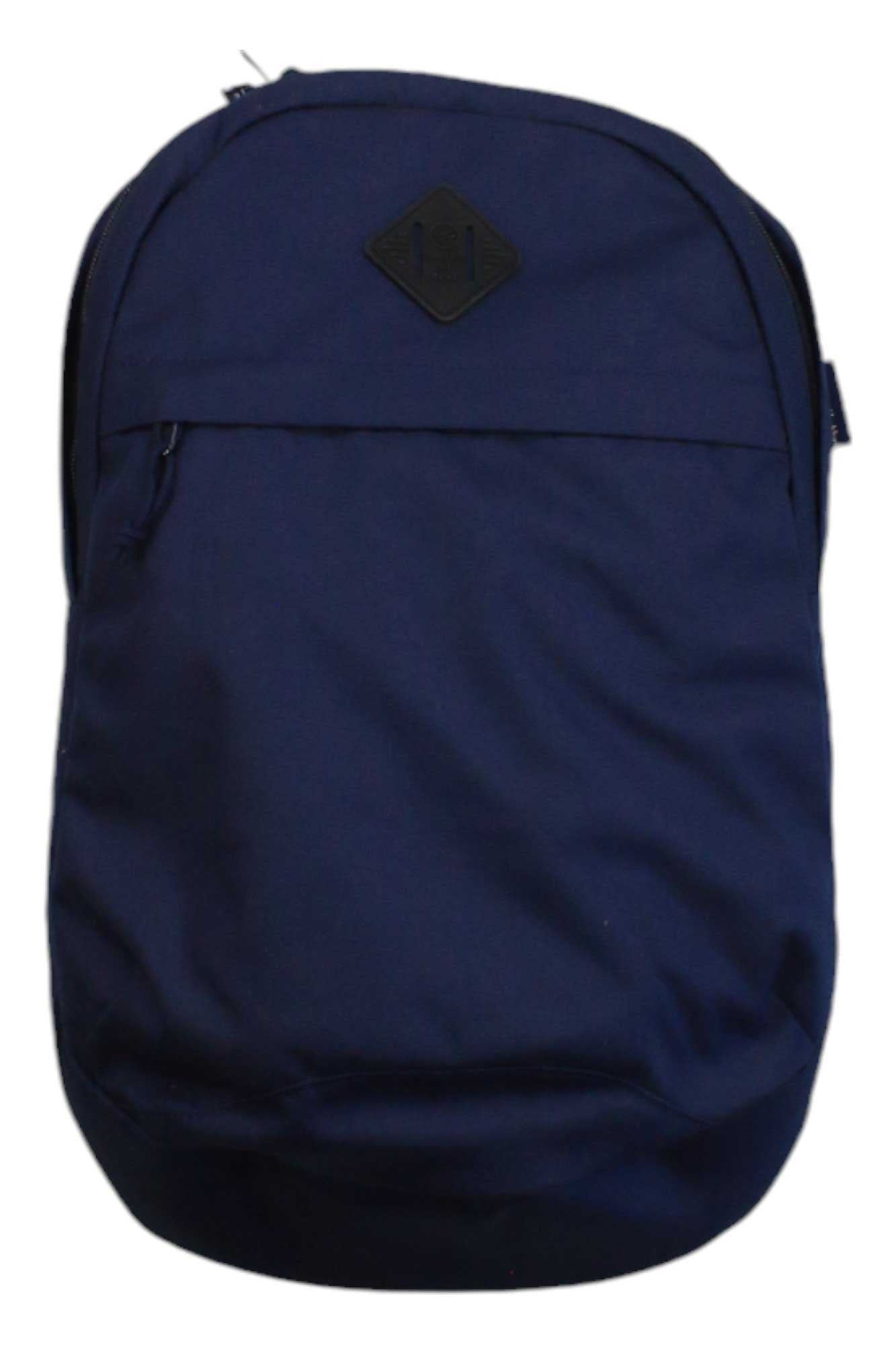 The United By Blue 15L Commuter Backpack is a navy blue, sustainable bag featuring a front zipper pocket and a black diamond patch near the top. Its simple design is displayed against a white background.
