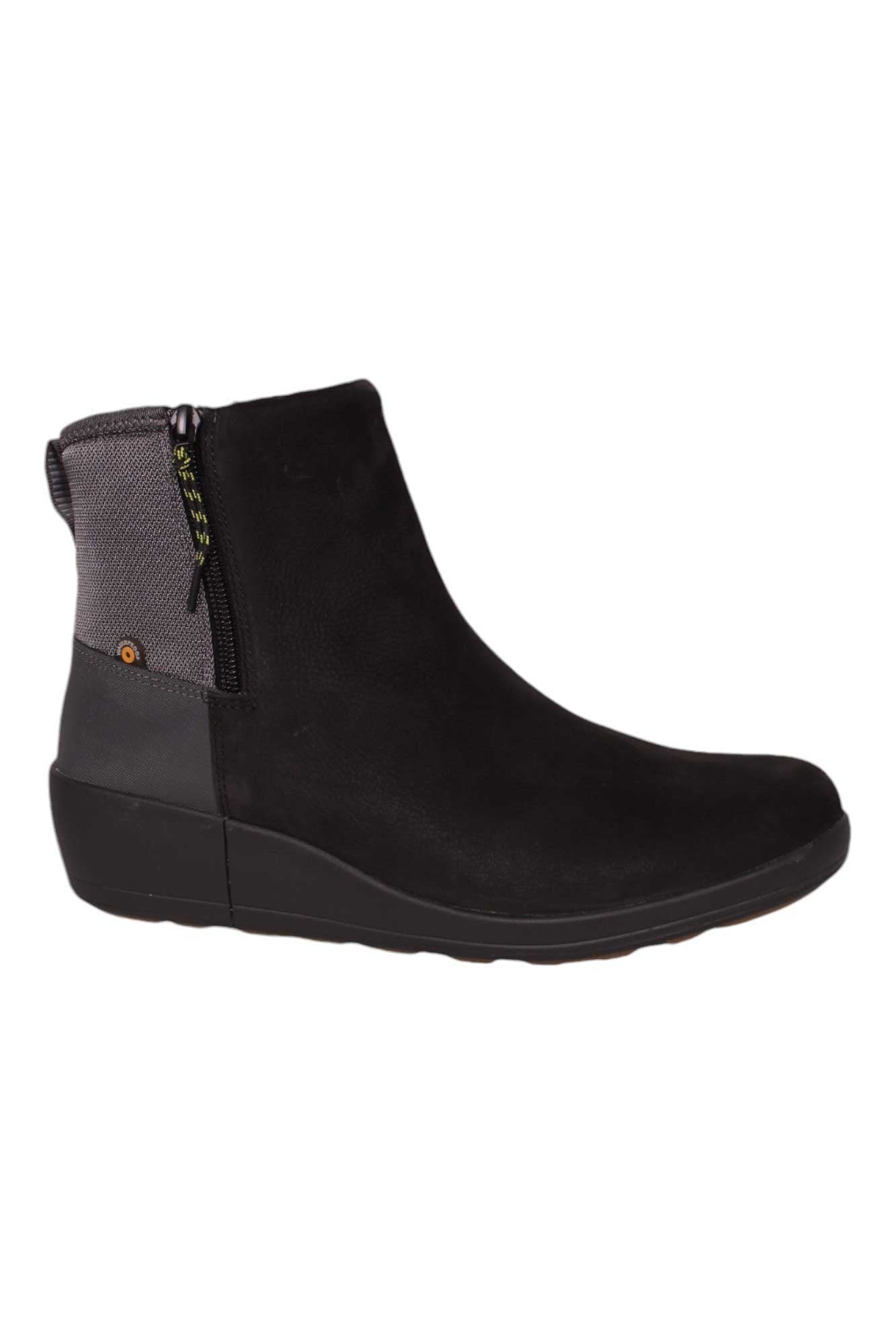The Bogs Women's Vista Rugged Zip Boot is a black, matte-finish boot made from eco-friendly materials, featuring a side zipper, gray textured heel detail, and a thick, slightly wedged sole for extra height.