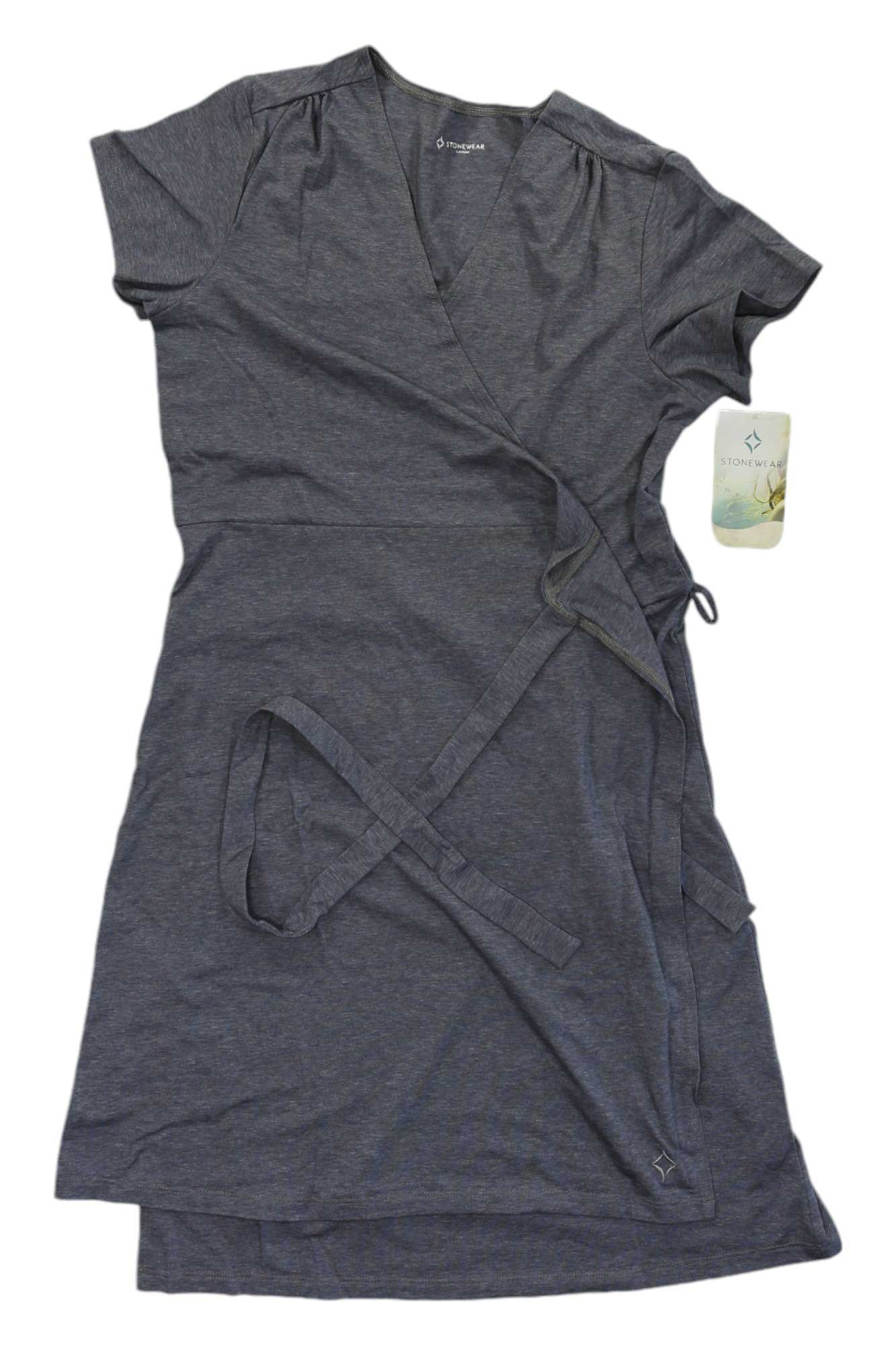 The Stonewear Designs Women's Orchard Dress is a short-sleeve, knee-length charcoal gray casual dress with a V-neckline and matching waist tie, shown flat with a tag attached.