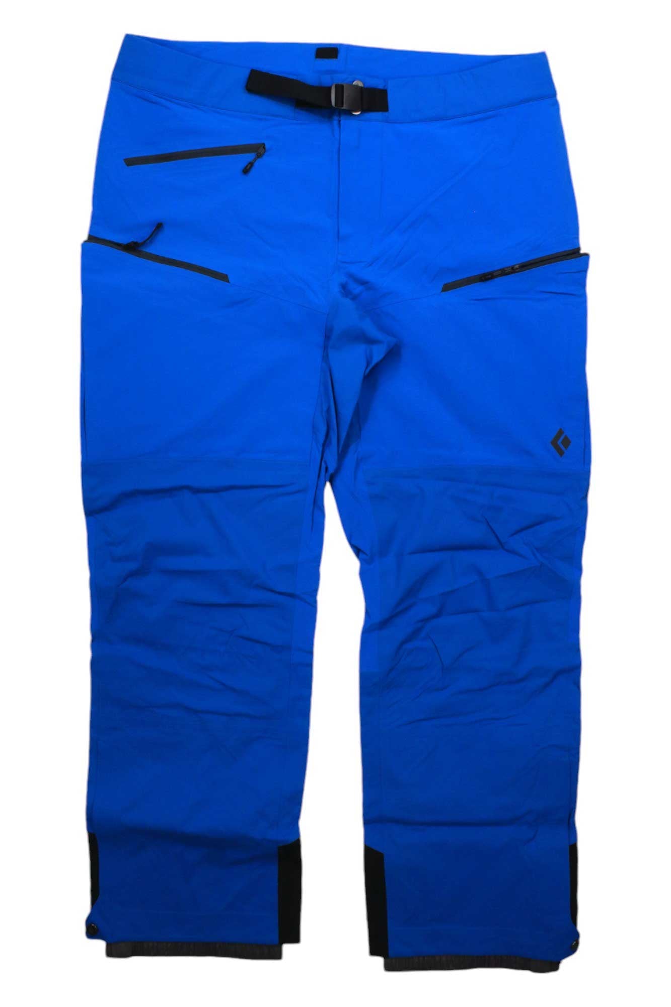 The Black Diamond Men's Dawn Patrol Hybrid Pant in bright blue features black zippered pockets, an integrated black belt, reinforced black ankle cuffs, and a small left thigh logo. Waterproof and breathable pants are displayed flat on a white background.
