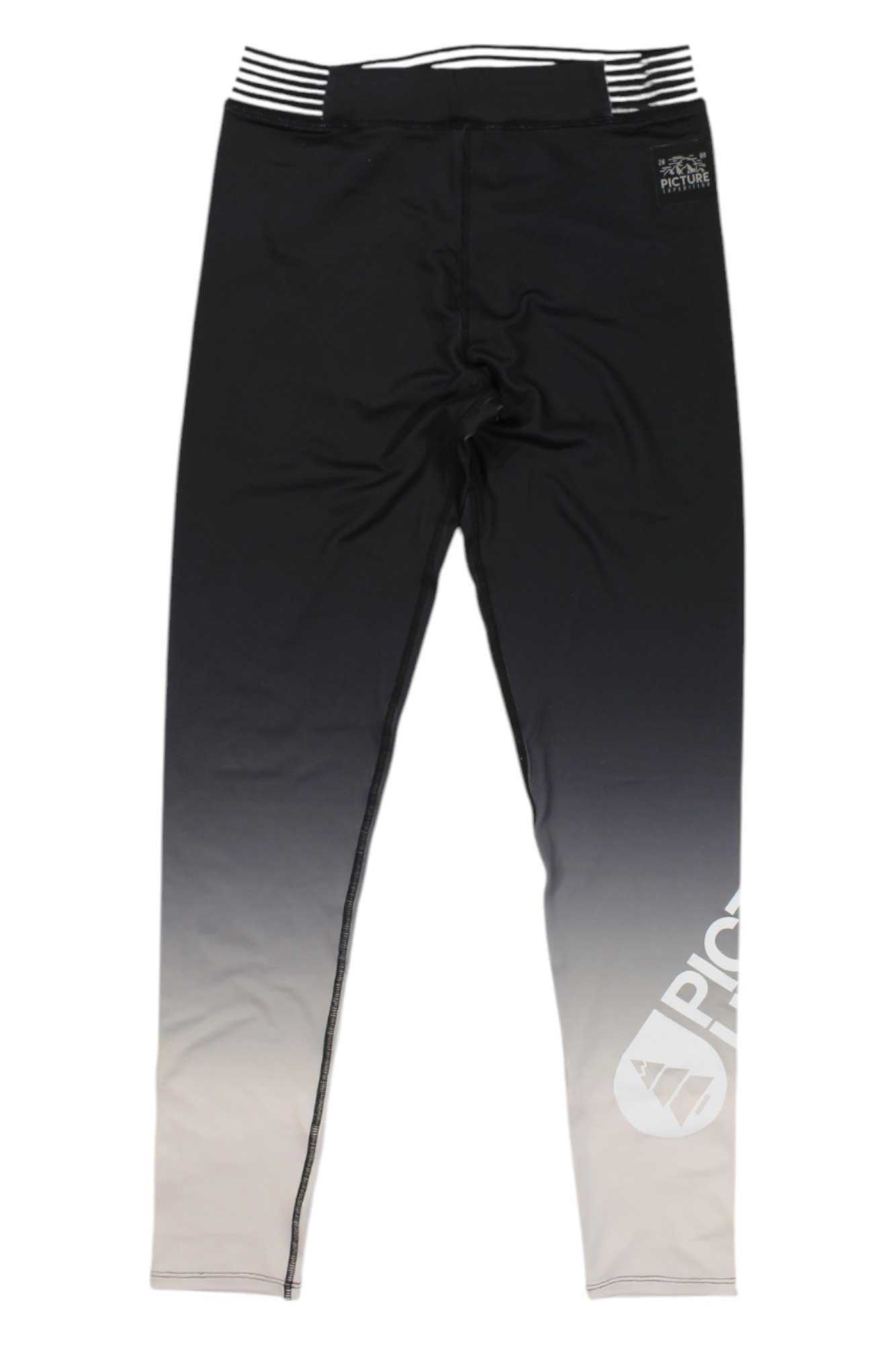 The Picture Women's Caty Tech Legging features a gradient from black at the waist to light gray at the ankles, a white geometric logo and text on the lower left leg, a black-and-white striped waistband, and moisture-wicking fabric.