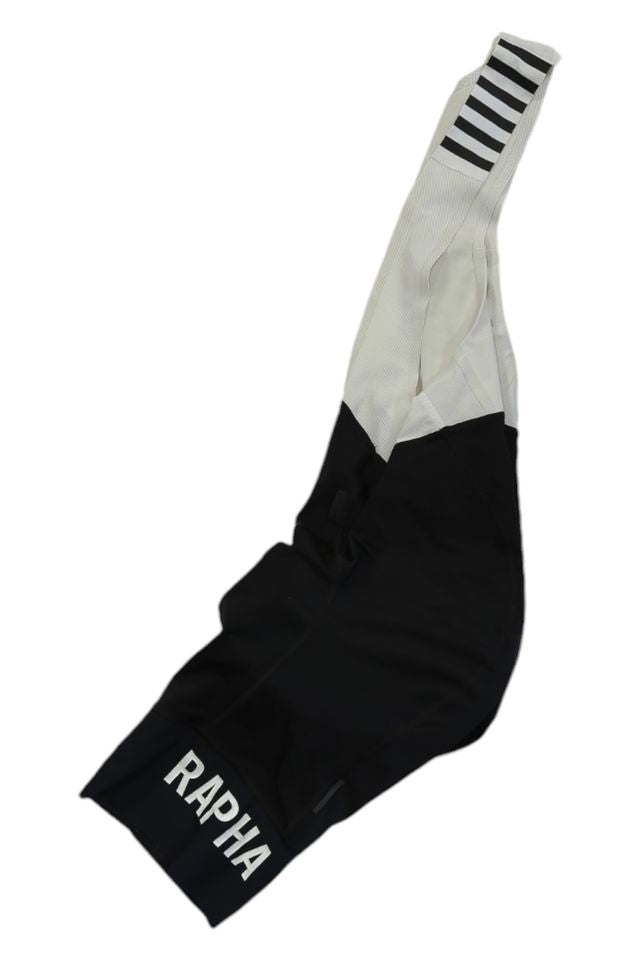 Rapha Mens Pro Team Bib Shorts II - Regular in black and white with “RAPHA” on the leg, black stripes on white shoulder straps, and a race-grade chamois—shown on a white background.