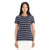 A person with long black hair wears the Icebreaker Womens Wave SS Stripe Tee, a navy blue top with white and light pink stripes made from Cool-Lite Merino Wool, paired with white pants and standing against a plain white background.