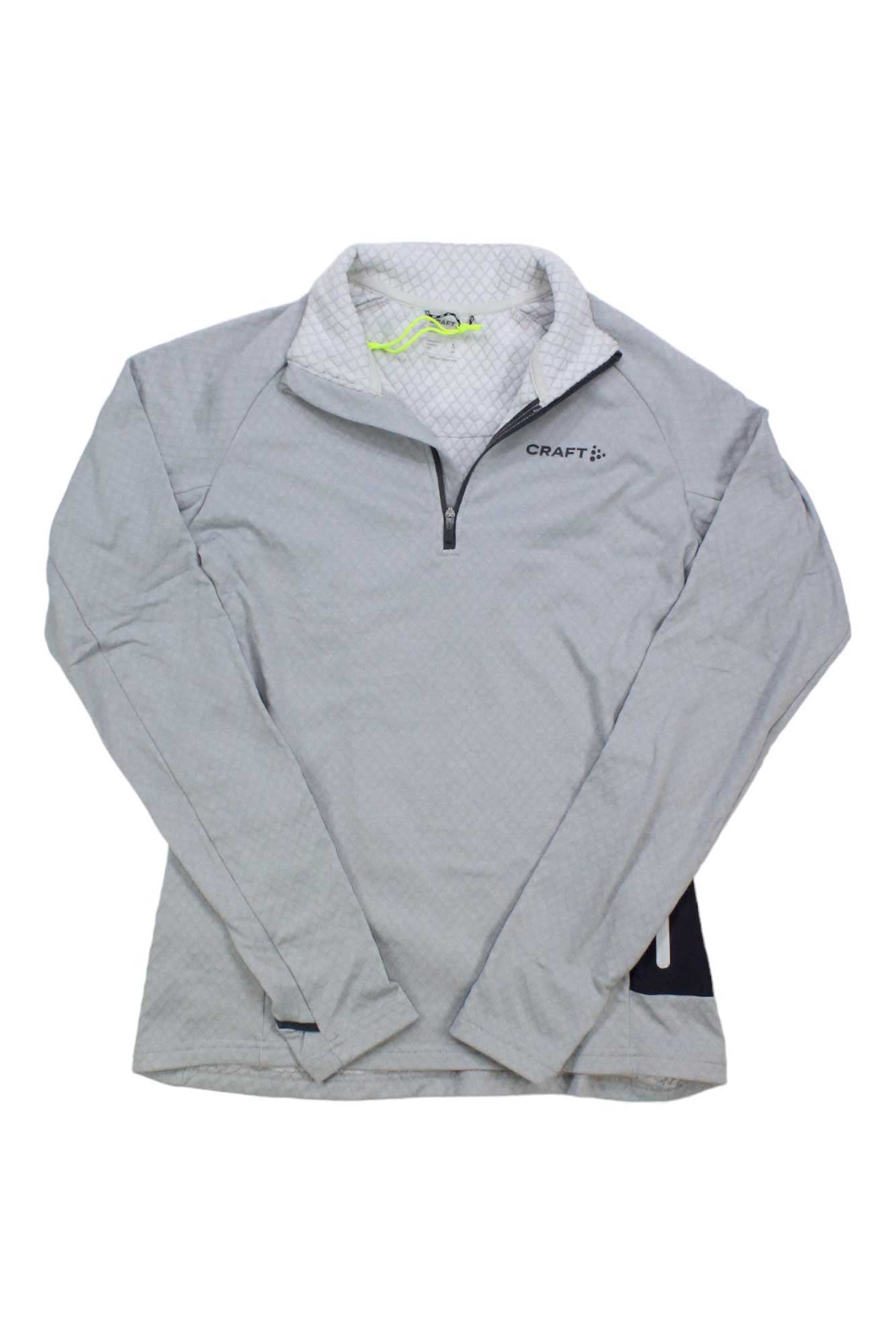 The Craft Sportswear Womens Core Trim Thermal Midlayer is a light gray pullover with a zip neck, stand-up collar, left chest Craft logo, and a white and yellow lining on the interior collar.