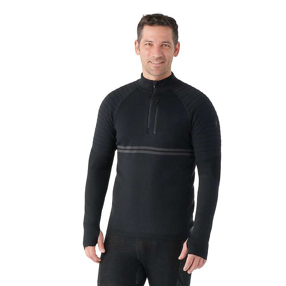 A man smiles against a white background, wearing the Smartwool Mens Intraknit Merino Tech 1/4 Zip Top—featuring ribbed sleeves and a horizontal chest stripe—ready for high-intensity activities.