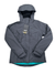 A dark gray Iceland Voyage 3-in-1 Jacket by Jack Wolfskin is laid flat with sleeves outstretched. A product tag hangs from the neck area, and the brand logo is visible on the left chest.