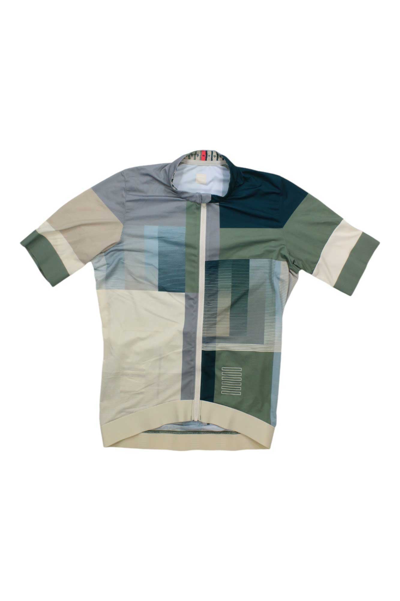 The Rapha Pro Team Training Jersey, a short-sleeve high-performance cycling top, features a geometric green, beige, gray, and blue pattern, front zipper, and high collar. Shown laid flat on a white background.