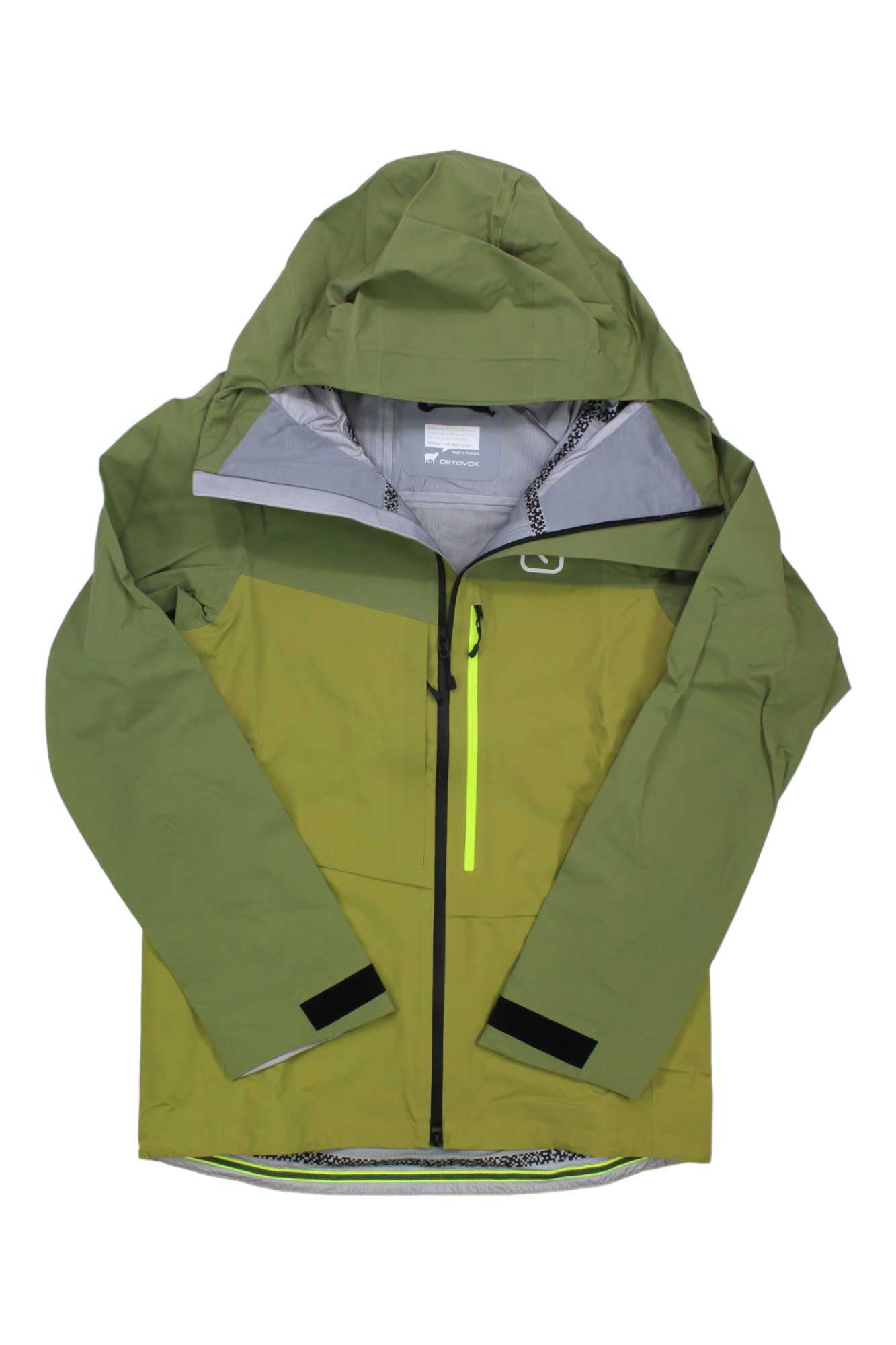 The Ortovox Men's Ravine 3L Shell Jacket is a green waterproof shell featuring a front zipper, bright yellow zippered chest pocket, and black adjustable cuffs—ideal for freeride skiing and shown on a white background.