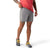 A person in a red shirt, Smartwool Mens Active Lined 5 Inch Short, and gray running shoes with yellow laces stands against a white background, lifting their shirt hem slightly.