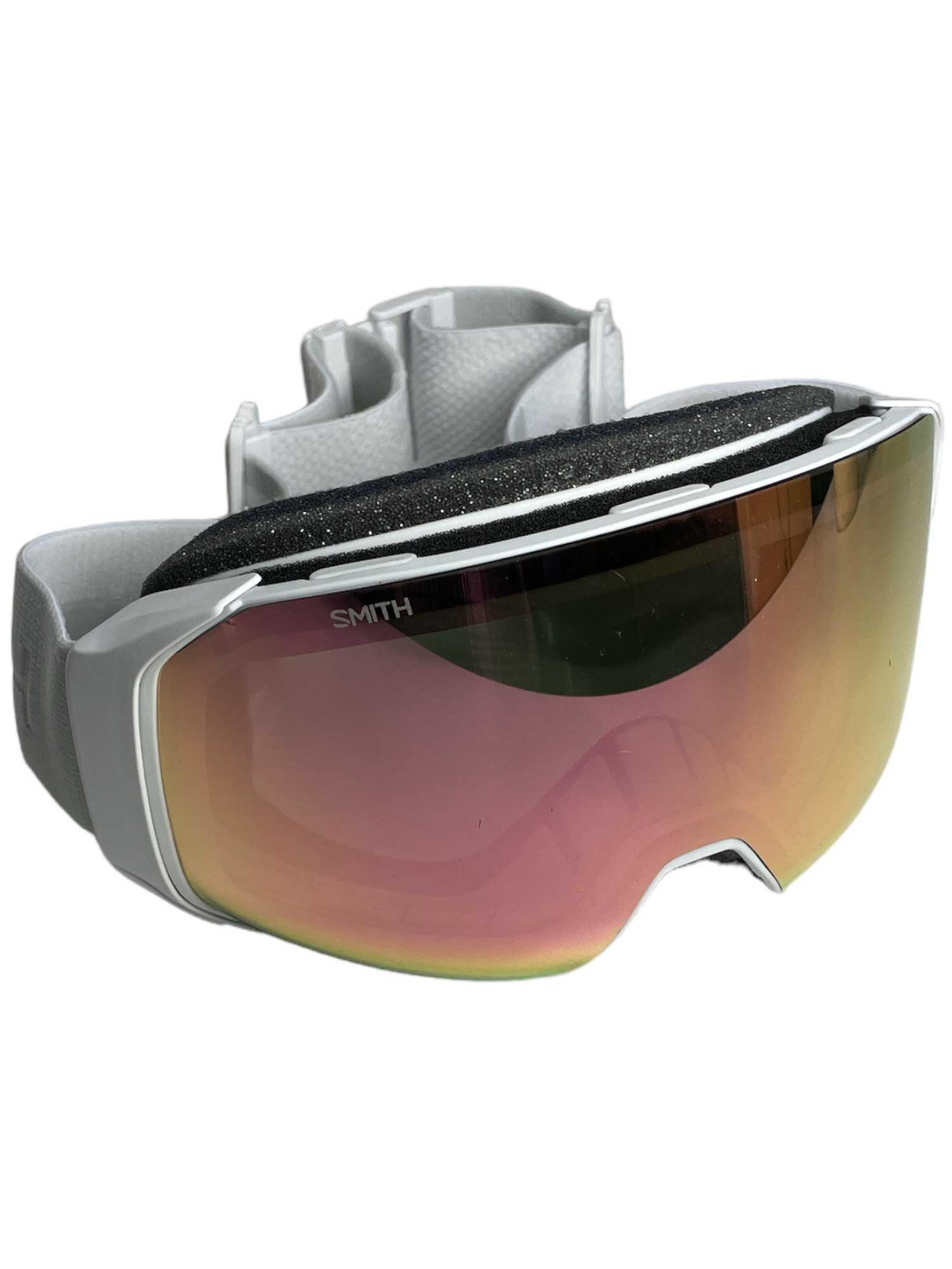 The Smith 4D Mag S Snow Goggle features a wide, reflective ChromaPop lens with a pink tint, anti-fog tech, black foam padding, and an adjustable white strap. “Smith” is printed on the upper edge of the lens.