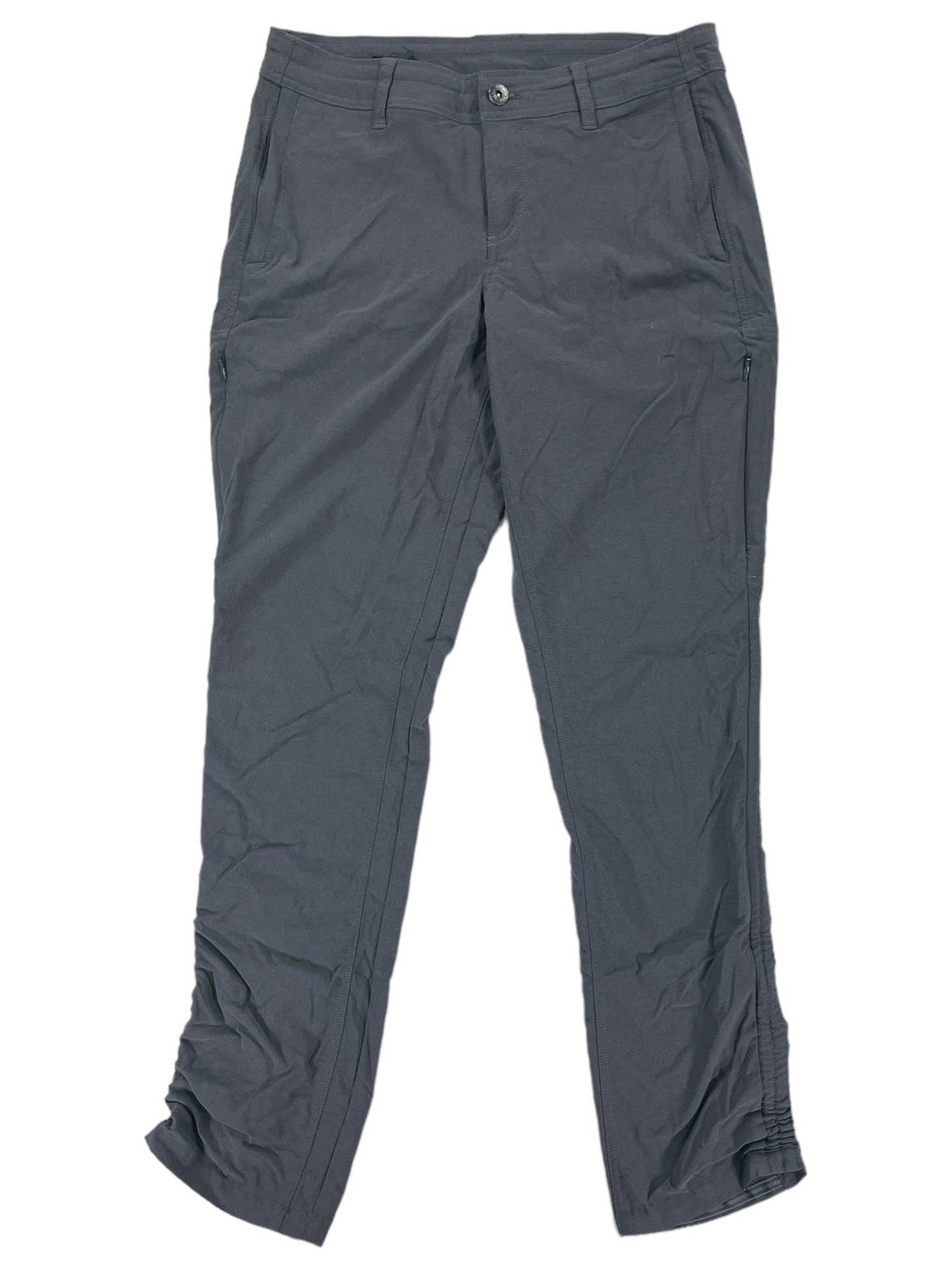 The Womens Trekr Pants in dark gray feature front pockets, belt loops, a button and zipper closure, and provide UPF 50 sun protection. They are shown laid flat on a white background.